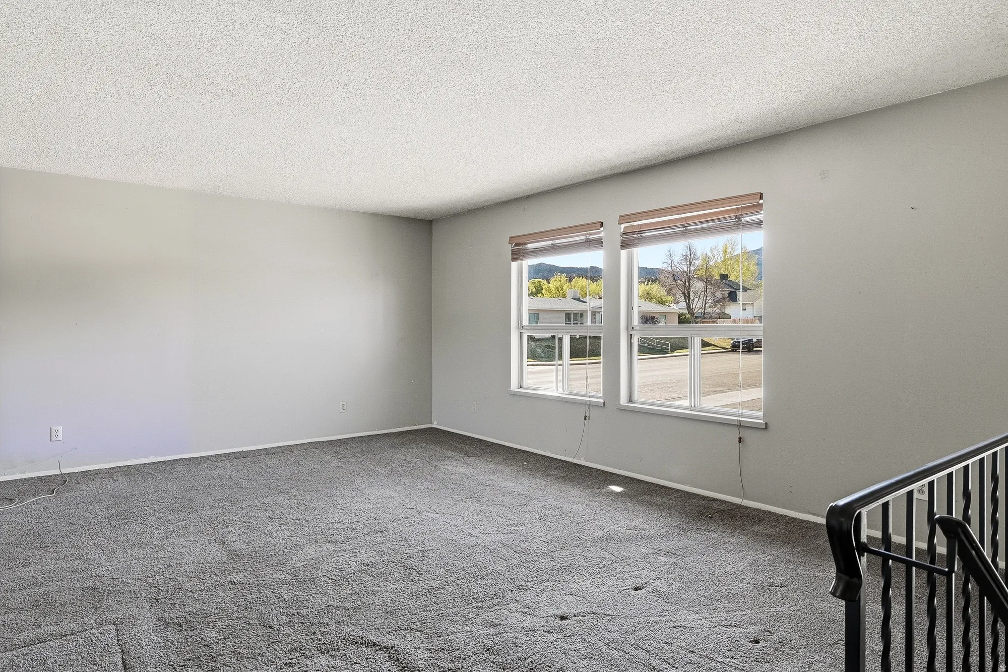 Carpeted spare room with a textured ceiling and baseboards