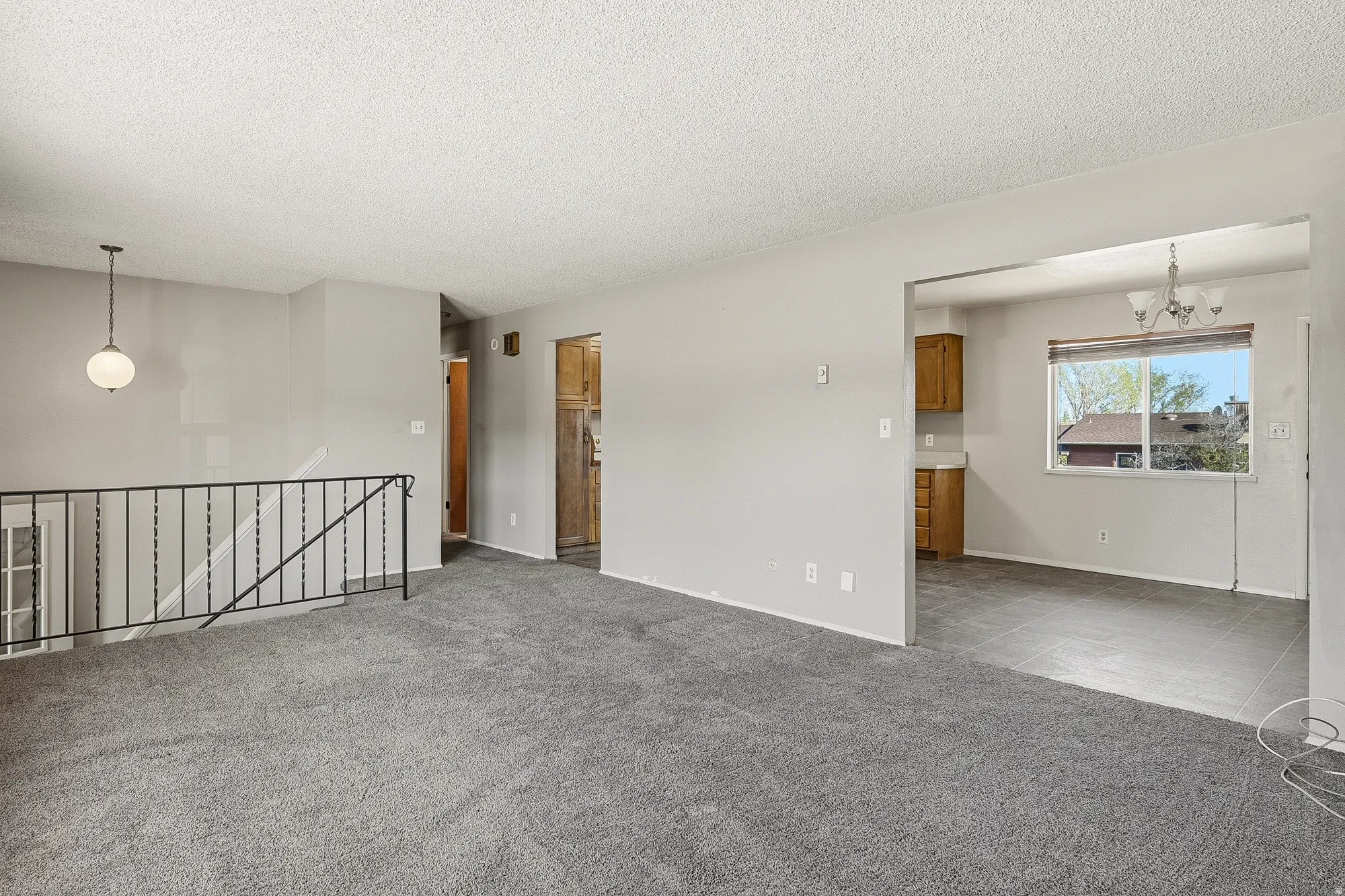 Spare room featuring a chandelier, light colored carpet, and a textured ceiling
