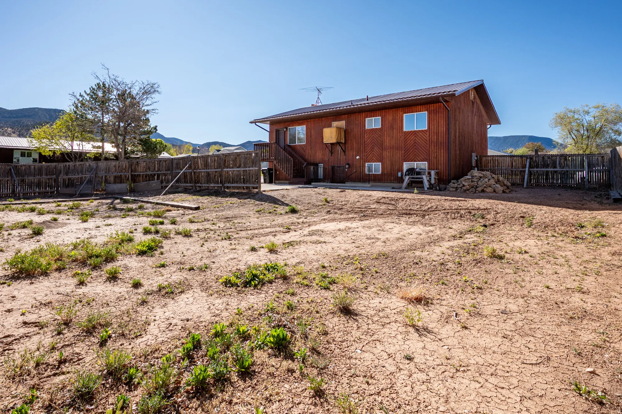 Back of house featuring a fenced backyard, a mountain view, a metal roof, and a patio
