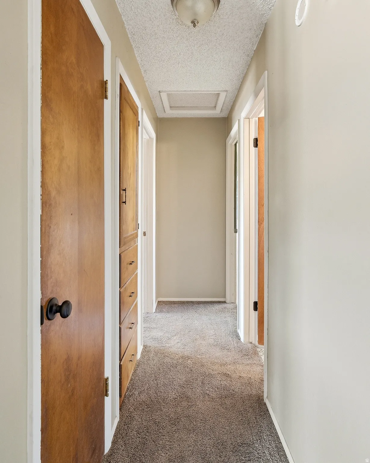 Hallway with a textured ceiling and light colored carpet