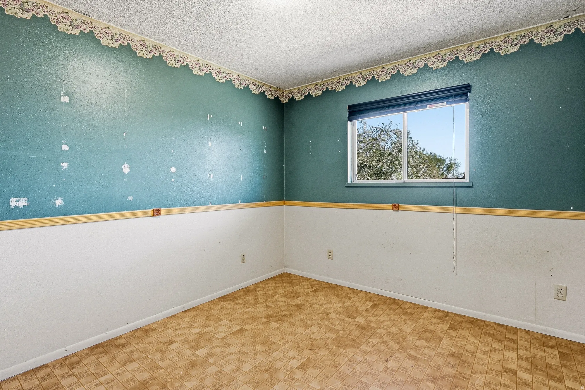 Empty room featuring a textured ceiling and tile patterned floors