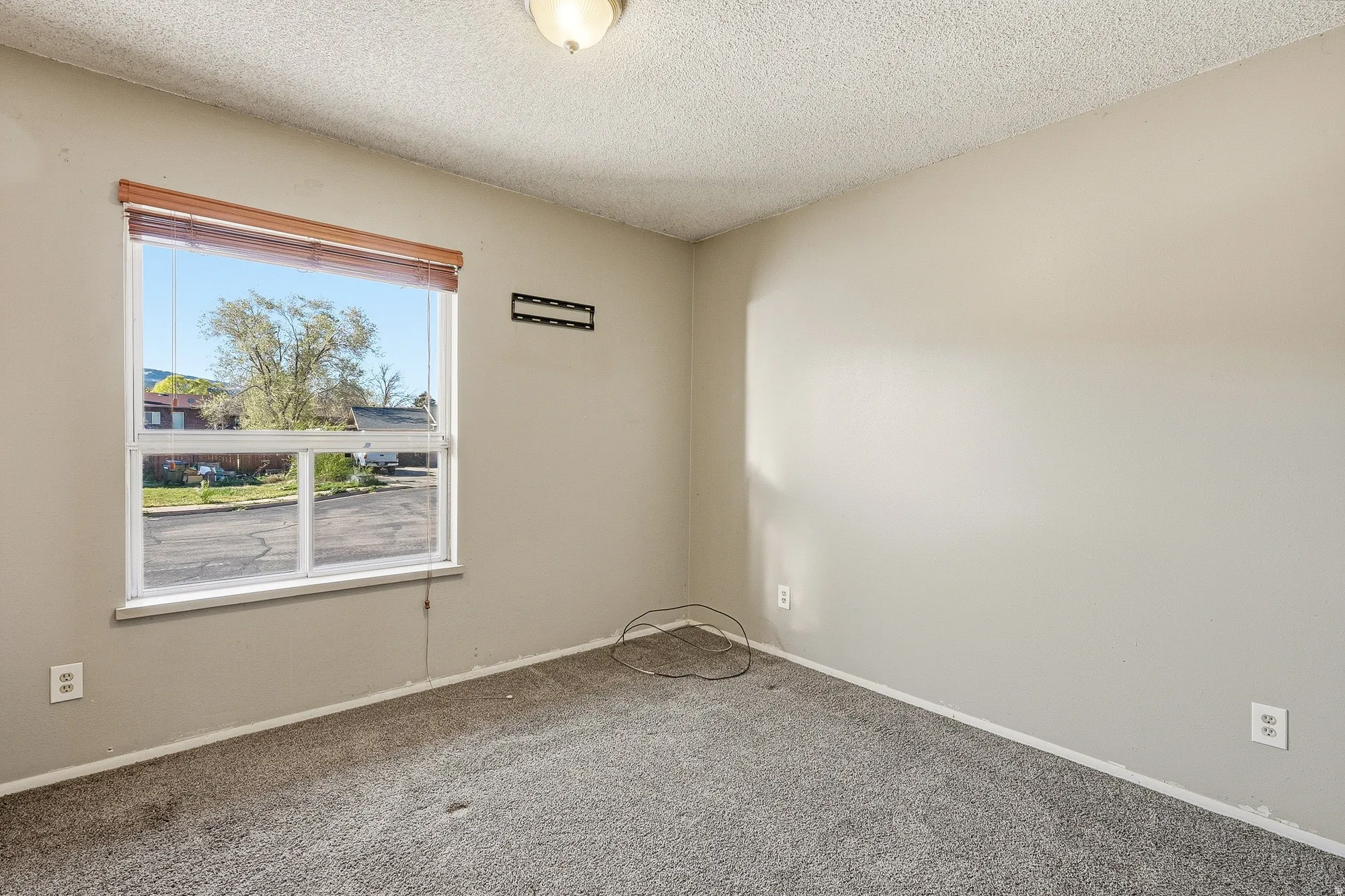 Carpeted empty room with a textured ceiling and baseboards