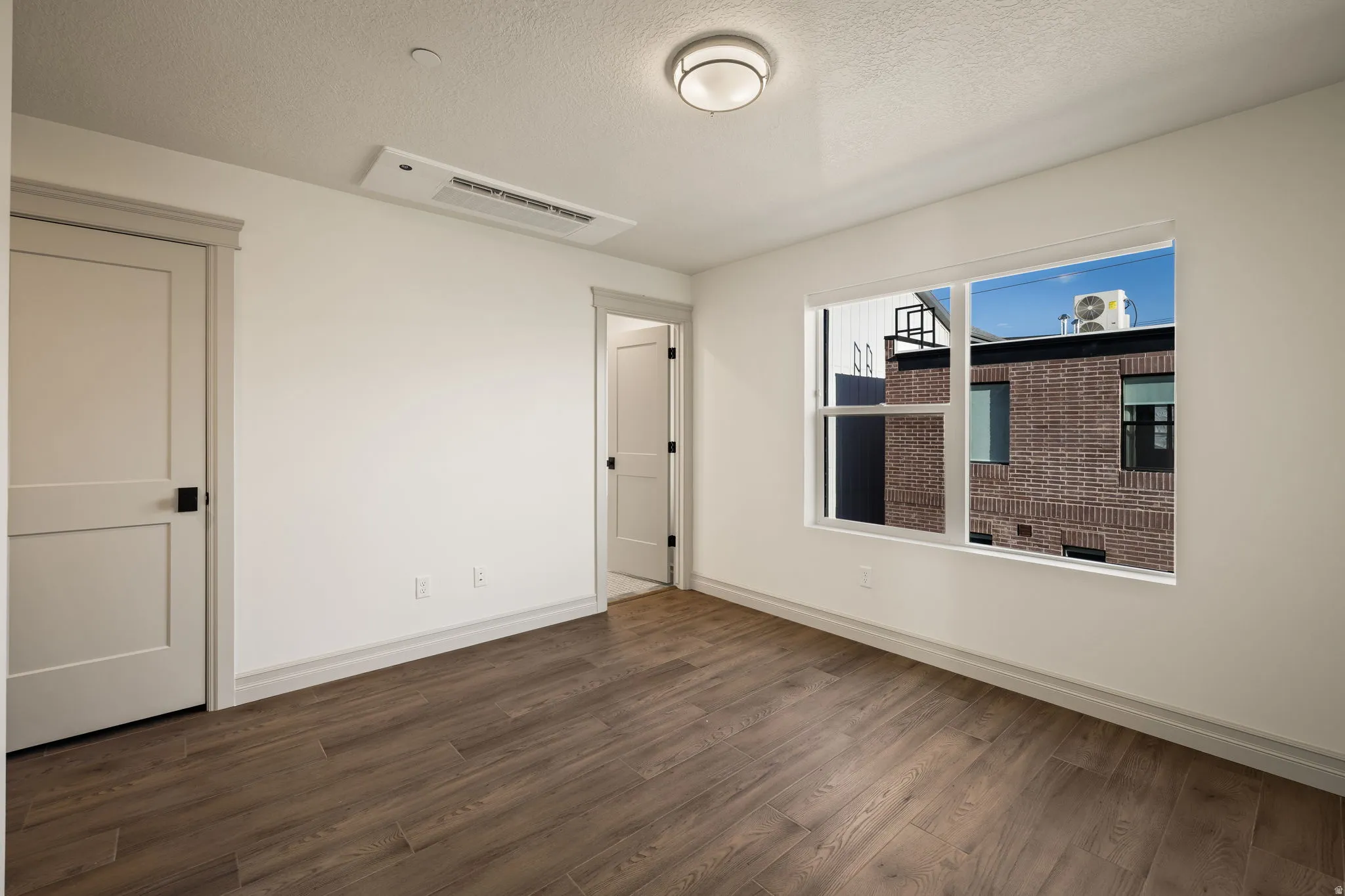 Photos of an exterior unit with the same finishes -Spare room with dark wood finished floors and a textured ceiling