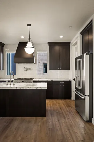 Photos of an exterior unit with the same finishes -Kitchen with high end refrigerator, dark wood finish cabinets, dark wood-style floors, light stone counters, and tasteful backsplash