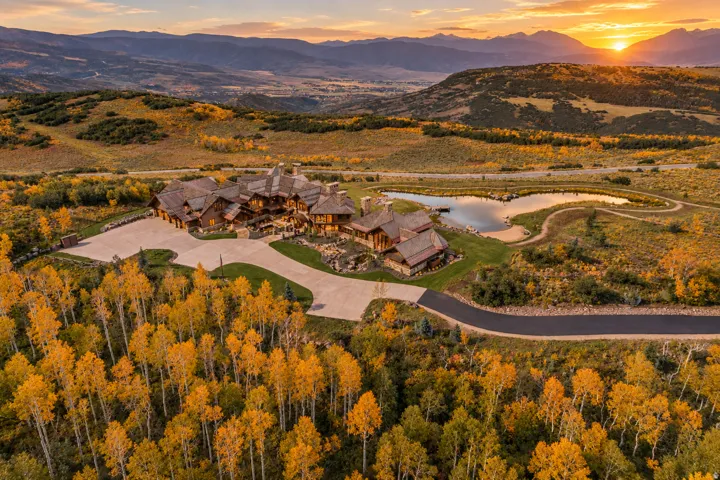 Expansive property featuring a large residence, winding driveway, and a private pond