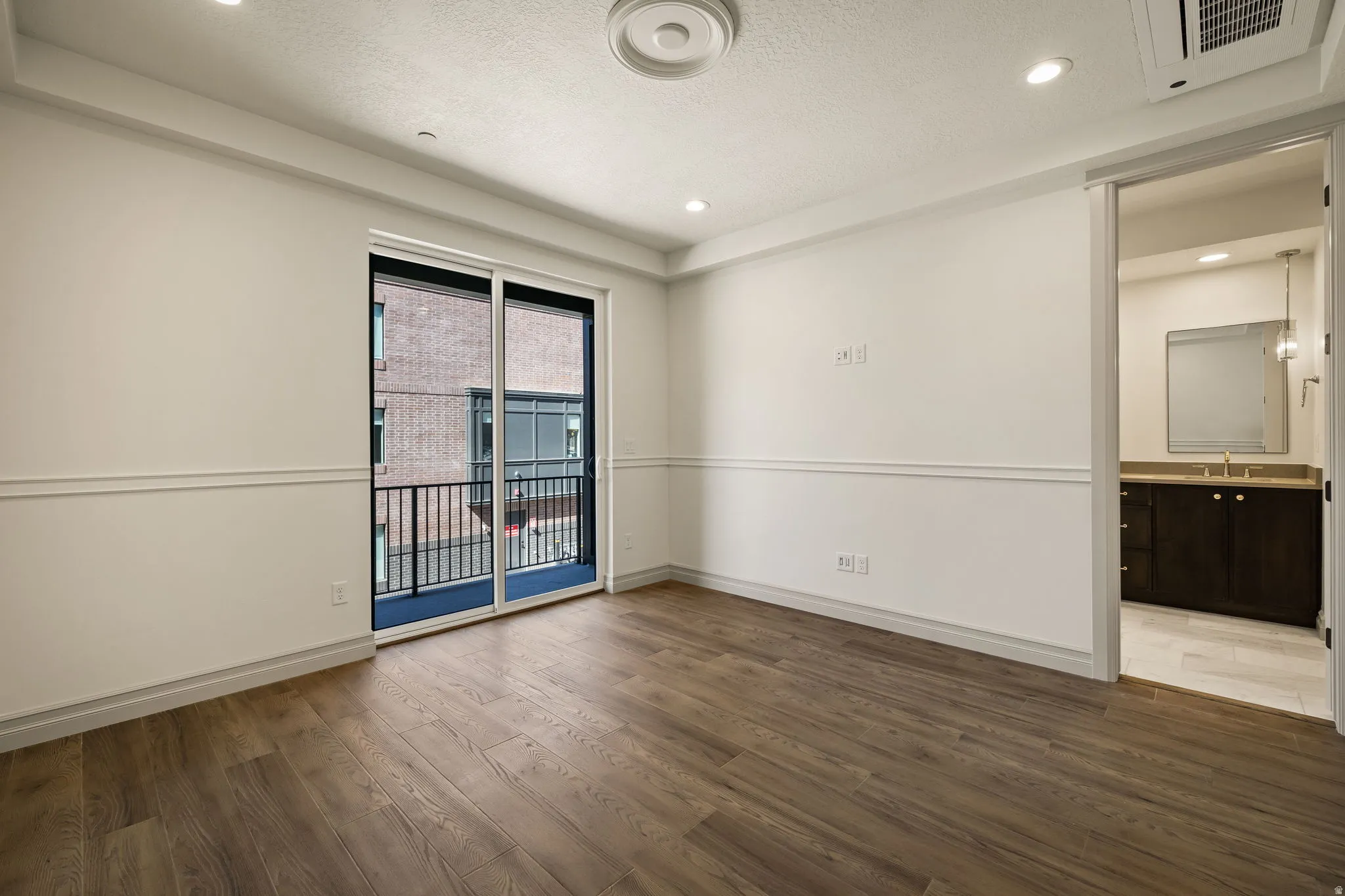 Empty room featuring dark wood-type flooring, a textured ceiling, and recessed lighting