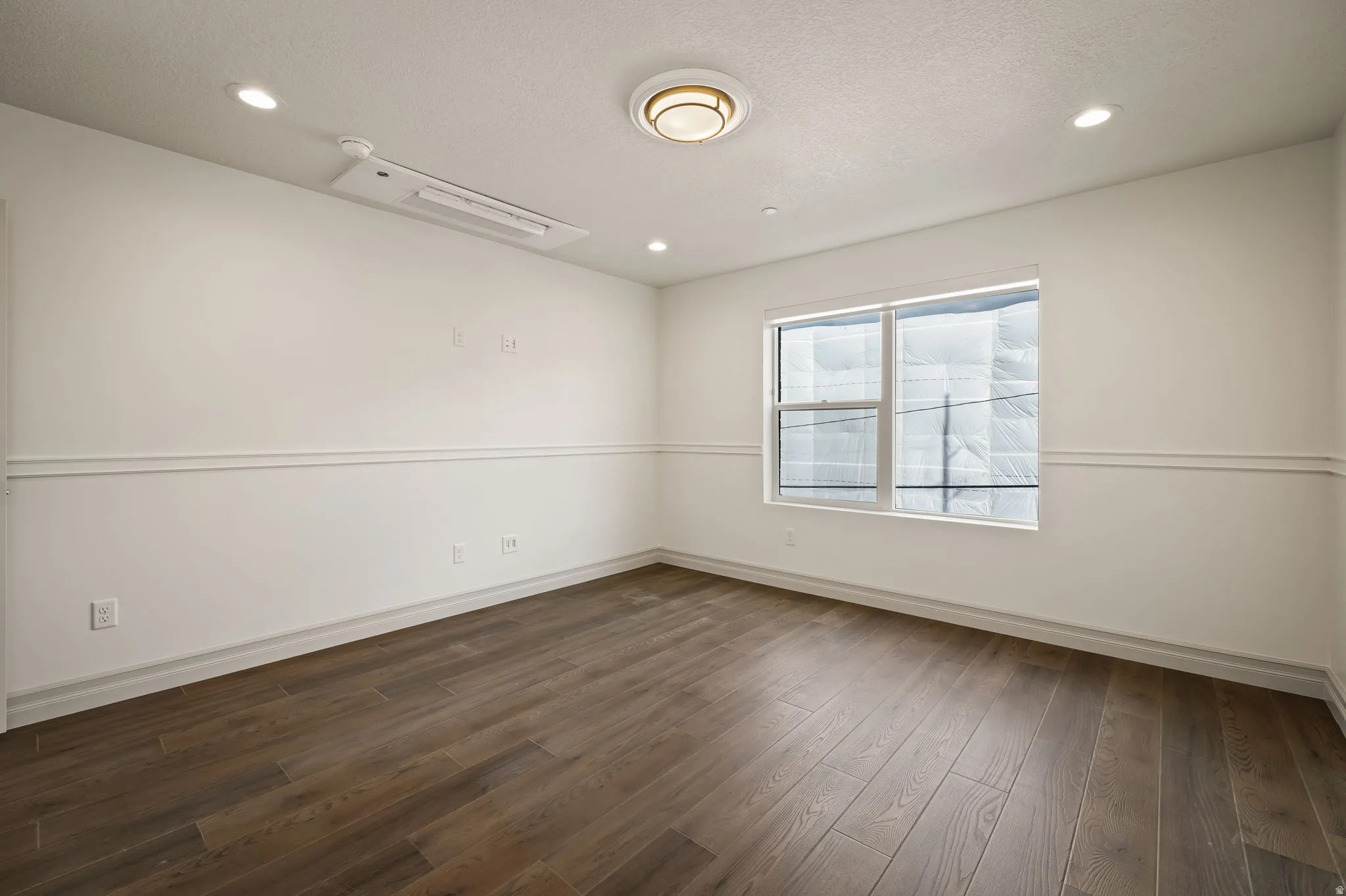 Empty room with recessed lighting, dark wood-type flooring, and a textured ceiling