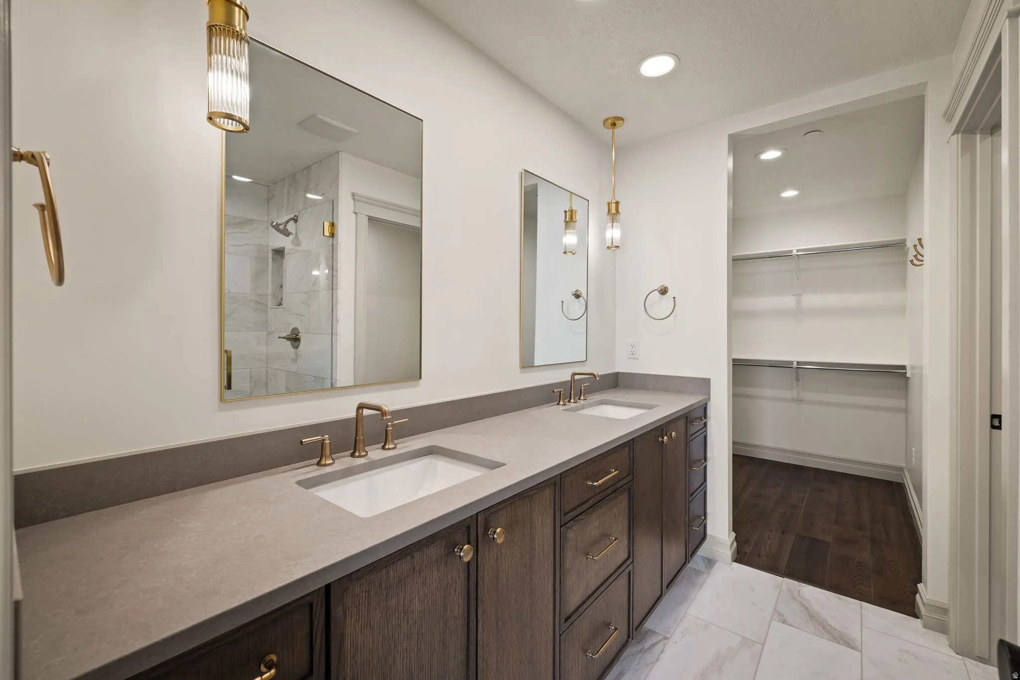 Full bathroom featuring double vanity, a spacious closet, a stall shower, light marble finish flooring, and recessed lighting