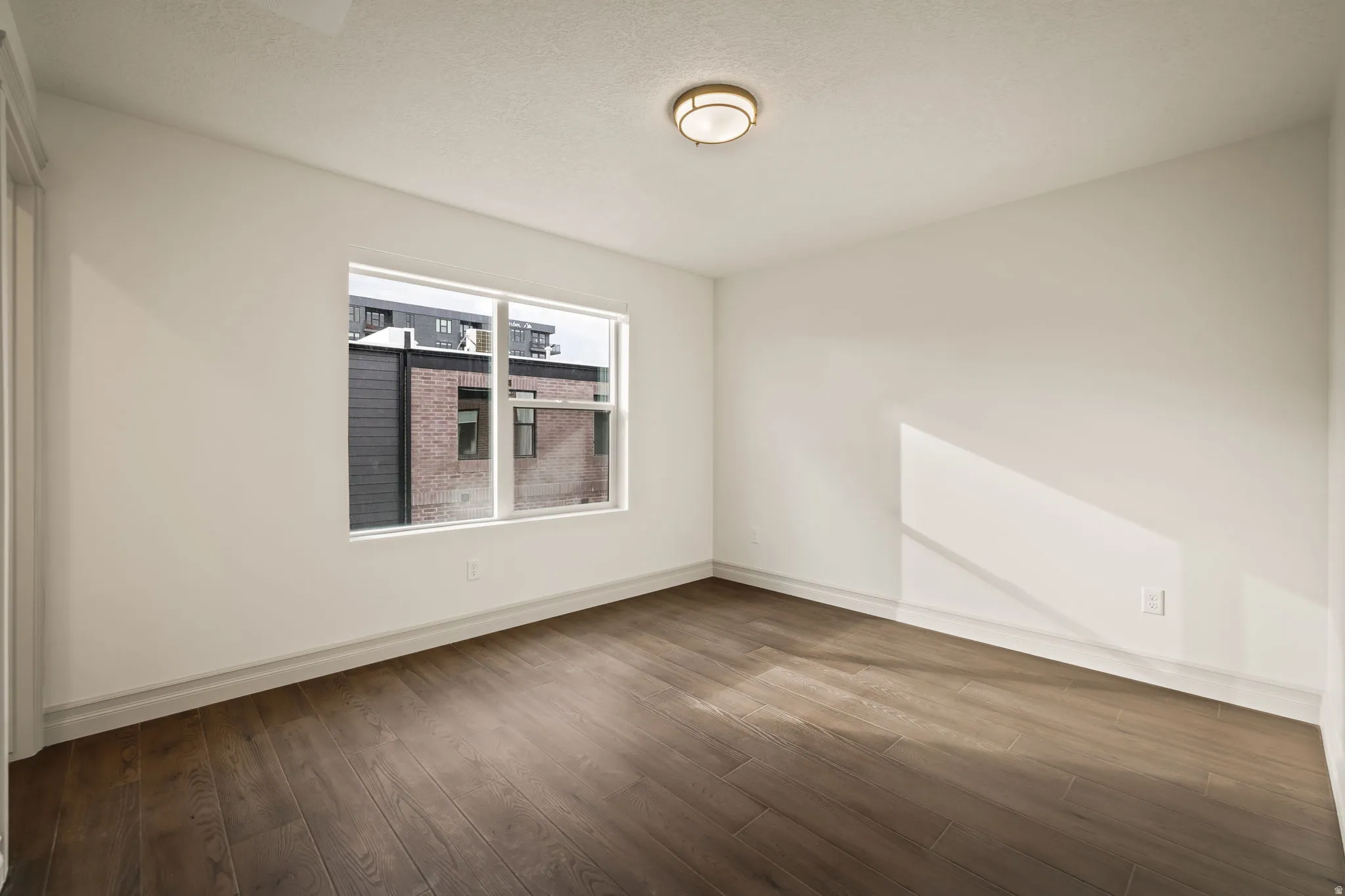 Unfurnished room featuring dark wood-type flooring and a textured ceiling