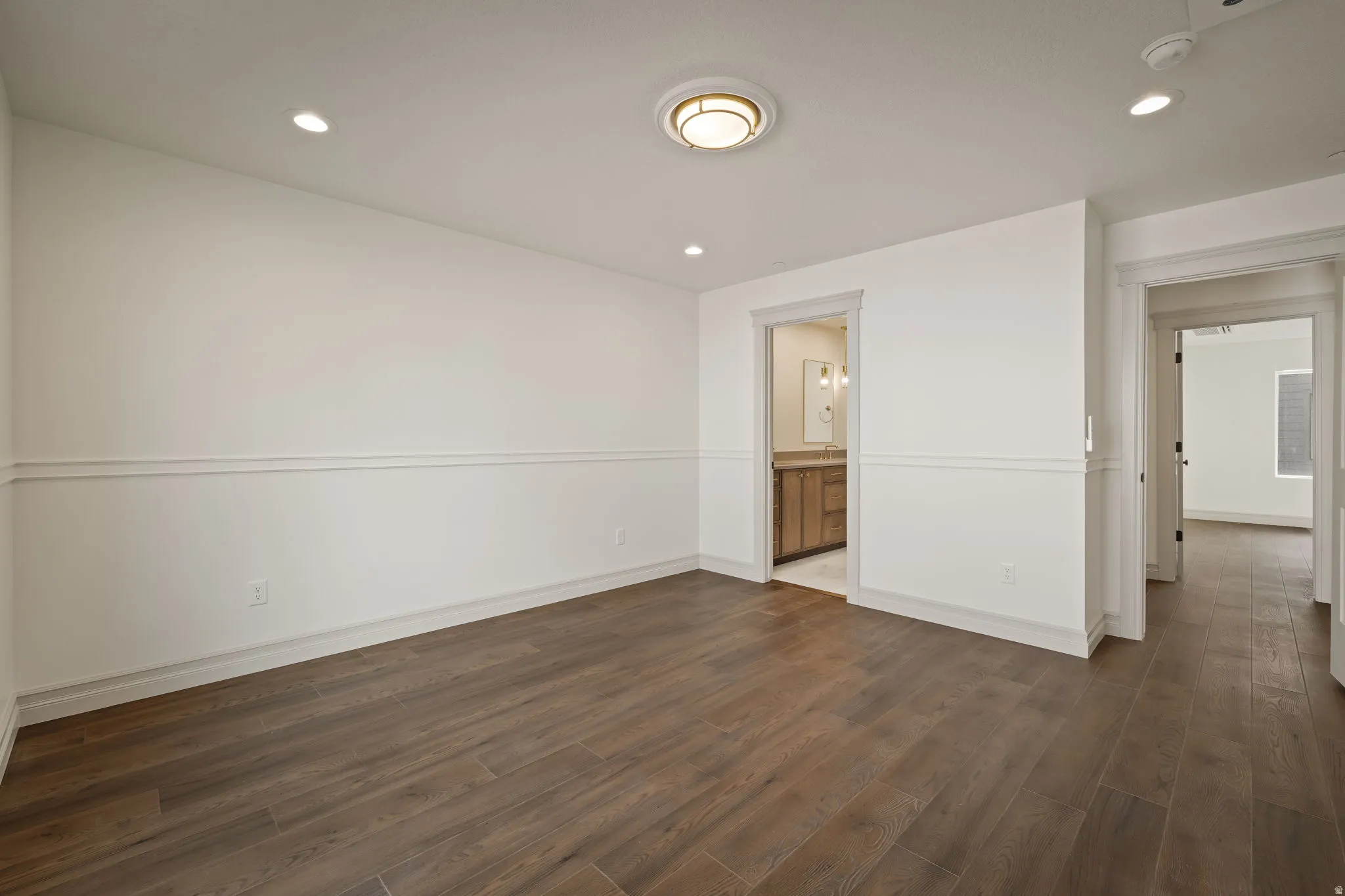 Unfurnished bedroom with dark wood-type flooring, recessed lighting, and ensuite bathroom