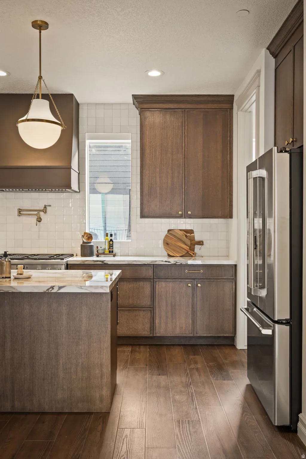 Kitchen with stainless steel appliances, dark wood-type flooring, backsplash, dark wood finish cabinetry, and pendant lighting