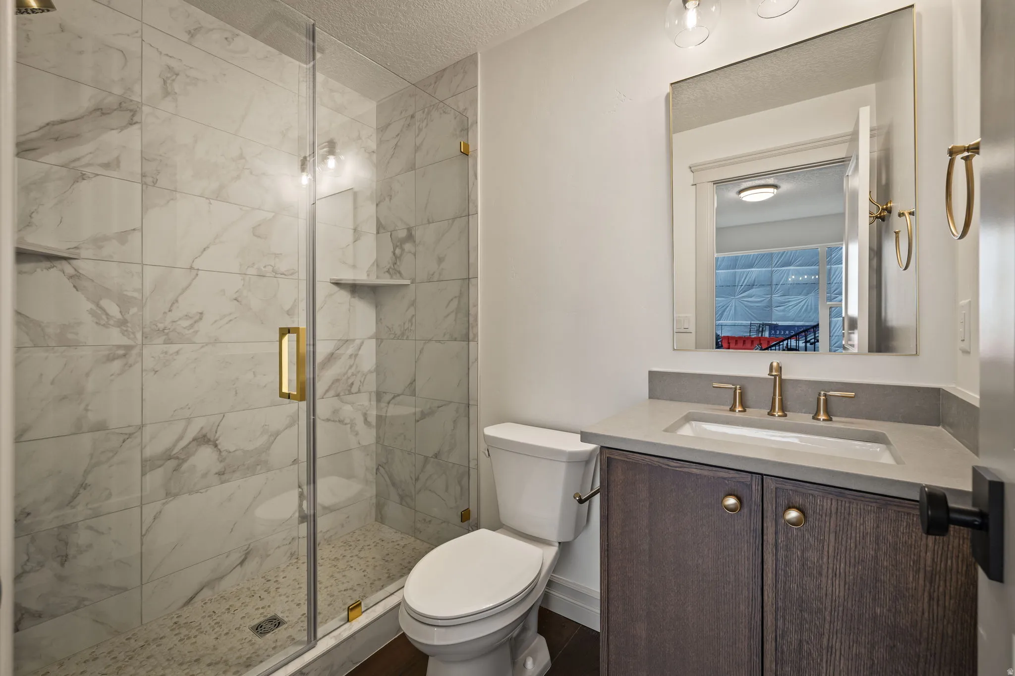 Ensuite bathroom featuring vanity, a marble finish shower, and a textured ceiling