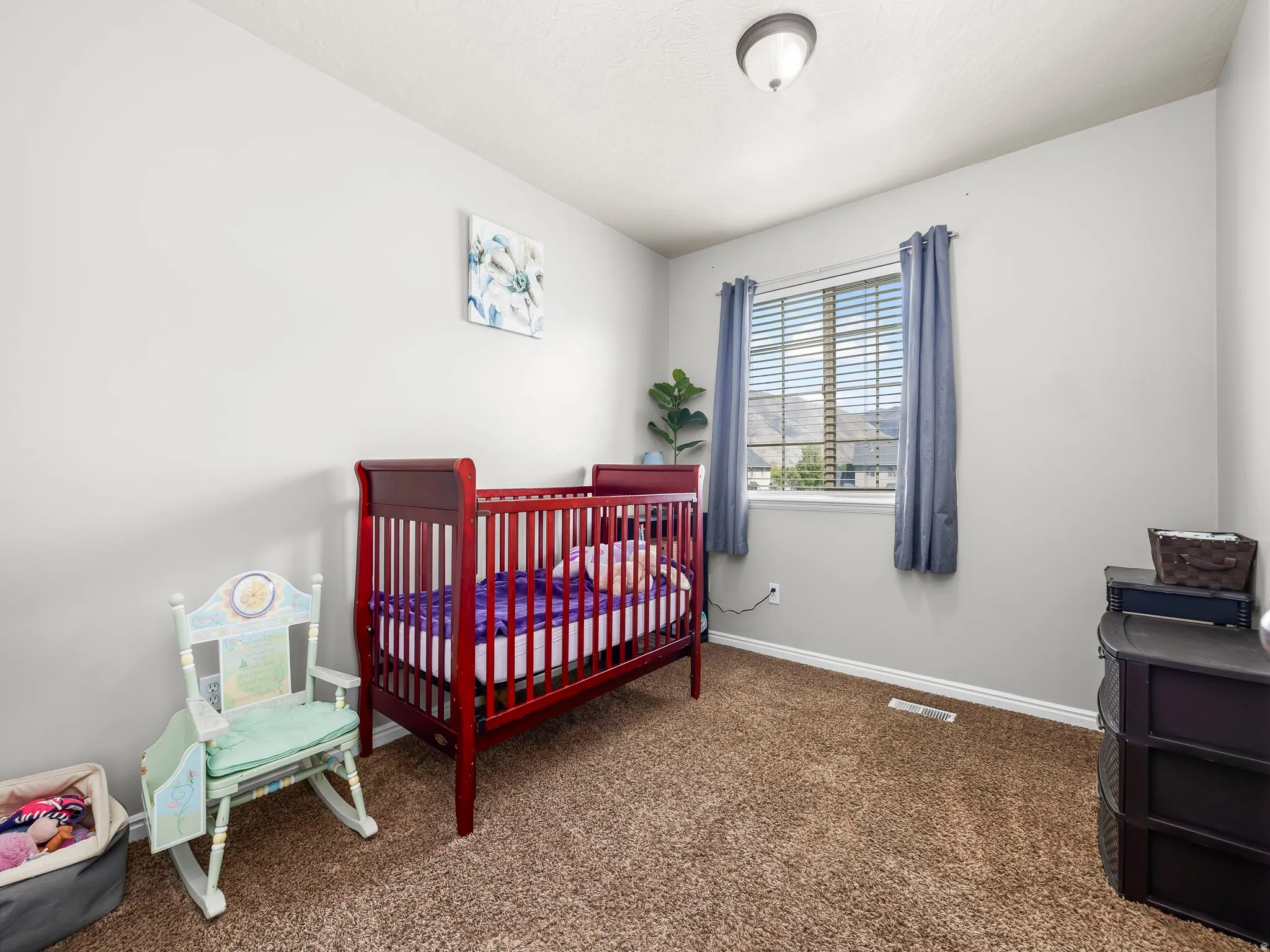 Bedroom featuring a crib and dark carpet