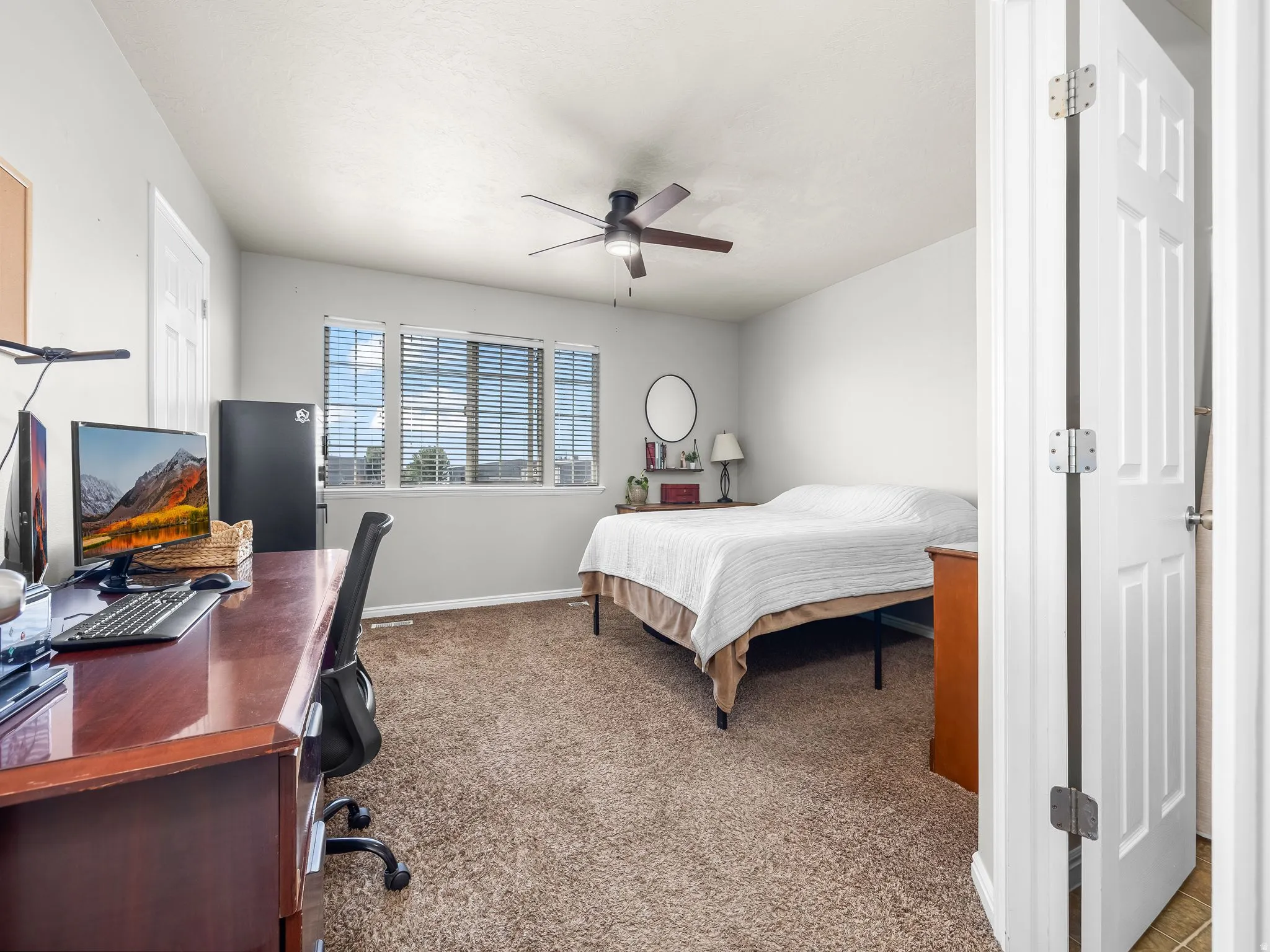 Bedroom with dark carpet, a desk, and a ceiling fan