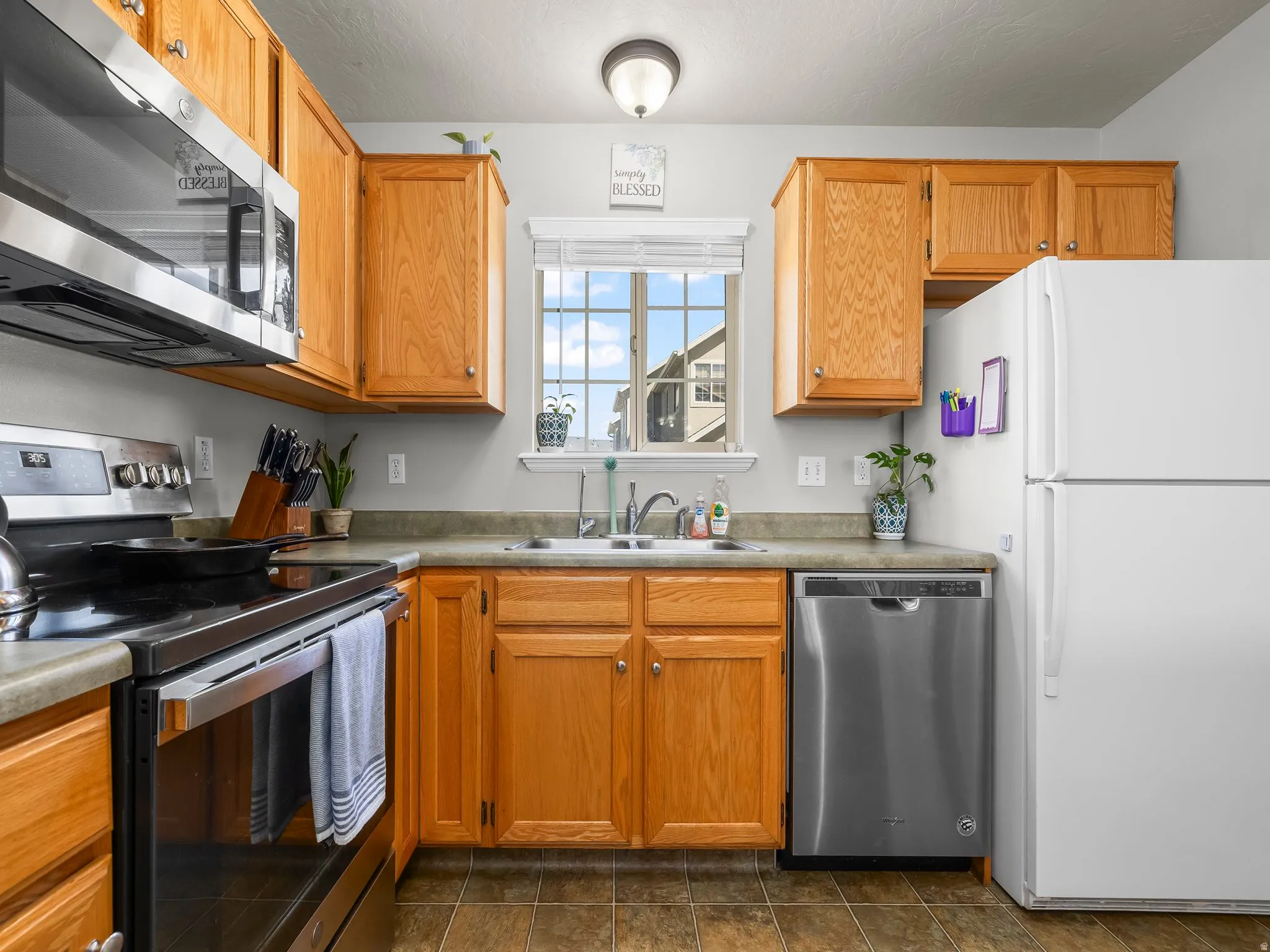 Kitchen with stainless steel appliances, light countertops, and wood finish cabinetry