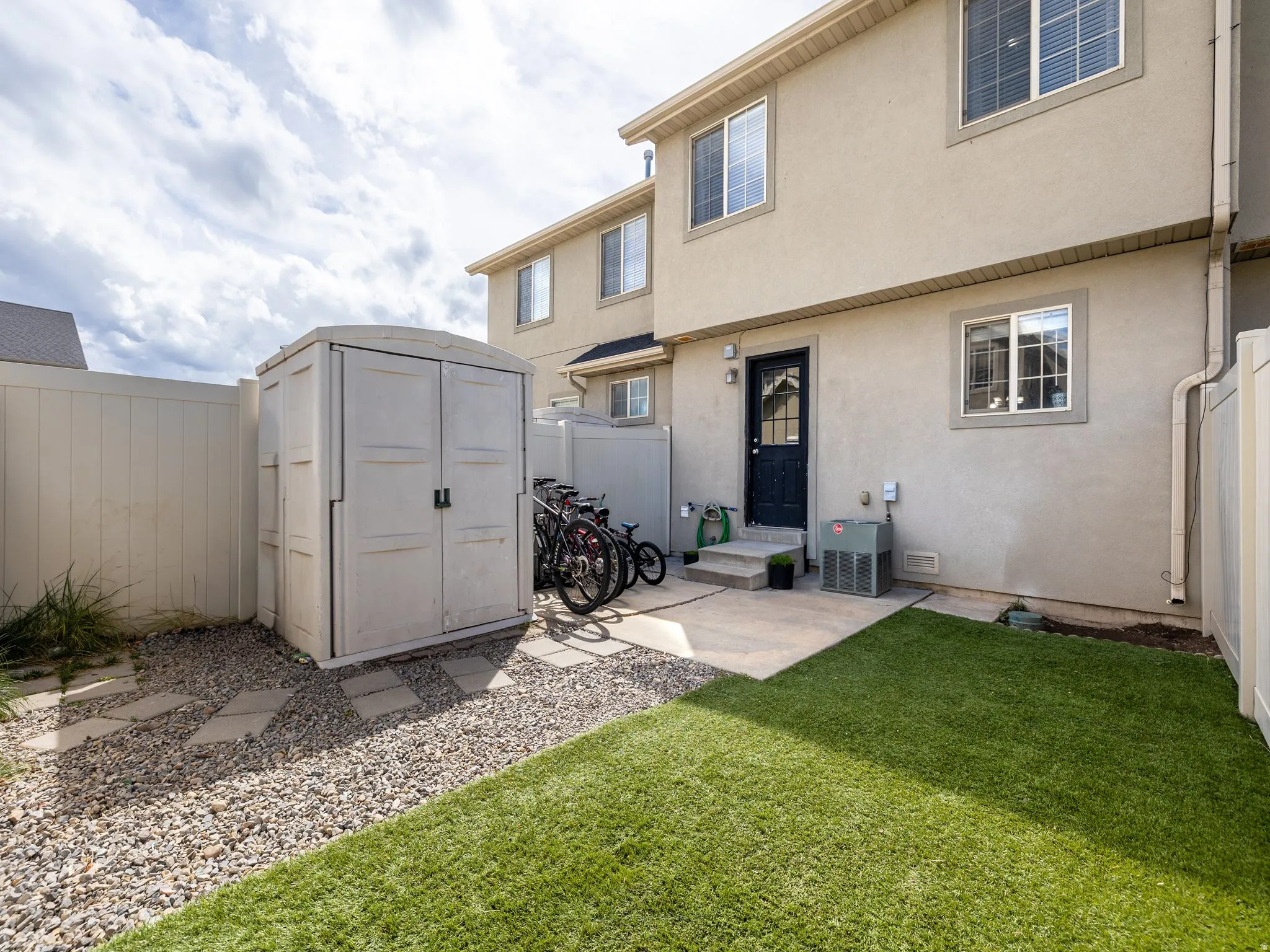 Rear view of property featuring a fenced backyard, stucco siding, and a storage unit