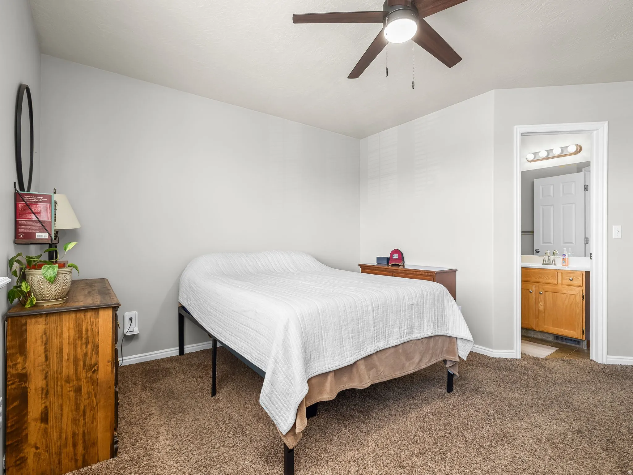 Bedroom featuring dark carpet, a ceiling fan, and ensuite bathroom