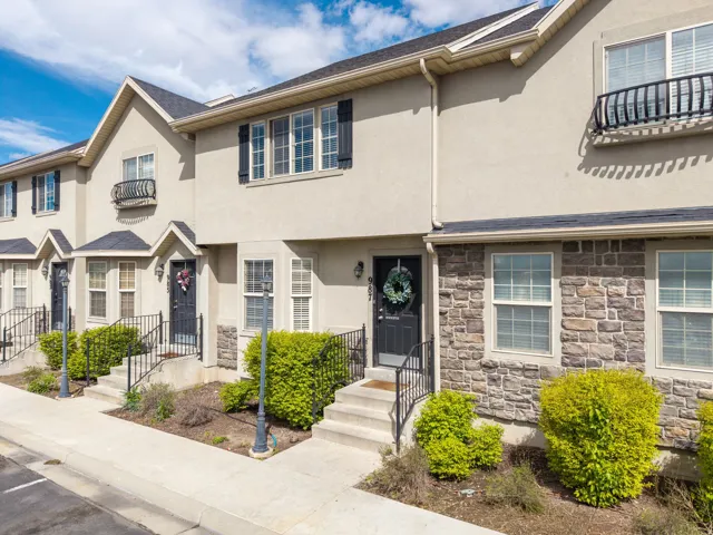 View of front of home with stone siding, stucco siding, and a balcony