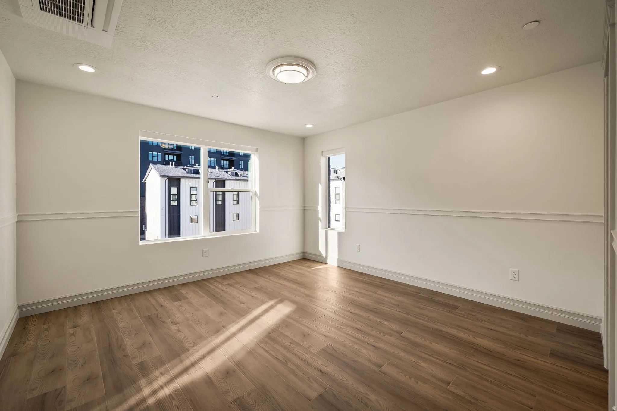 Empty room featuring a textured ceiling, recessed lighting, and dark wood-style flooring
