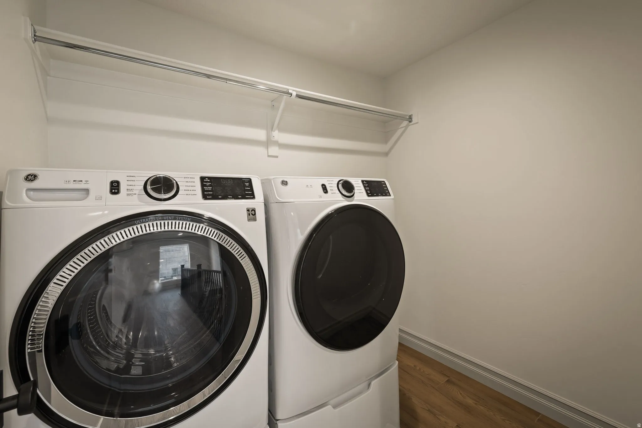 Laundry area with dark wood-type flooring and separate washer and dryer