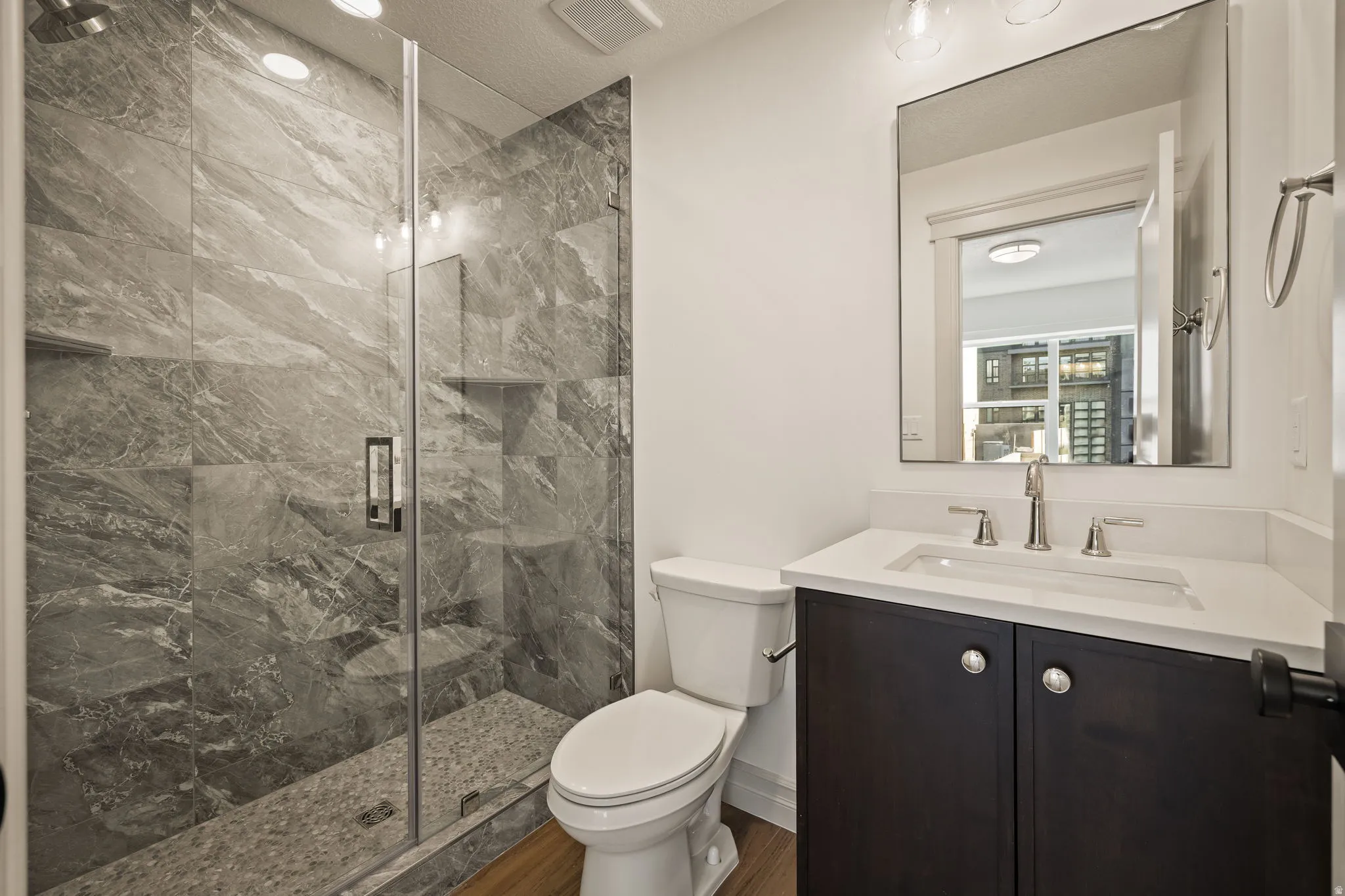 Bathroom with vanity, a marble finish shower, and a textured ceiling