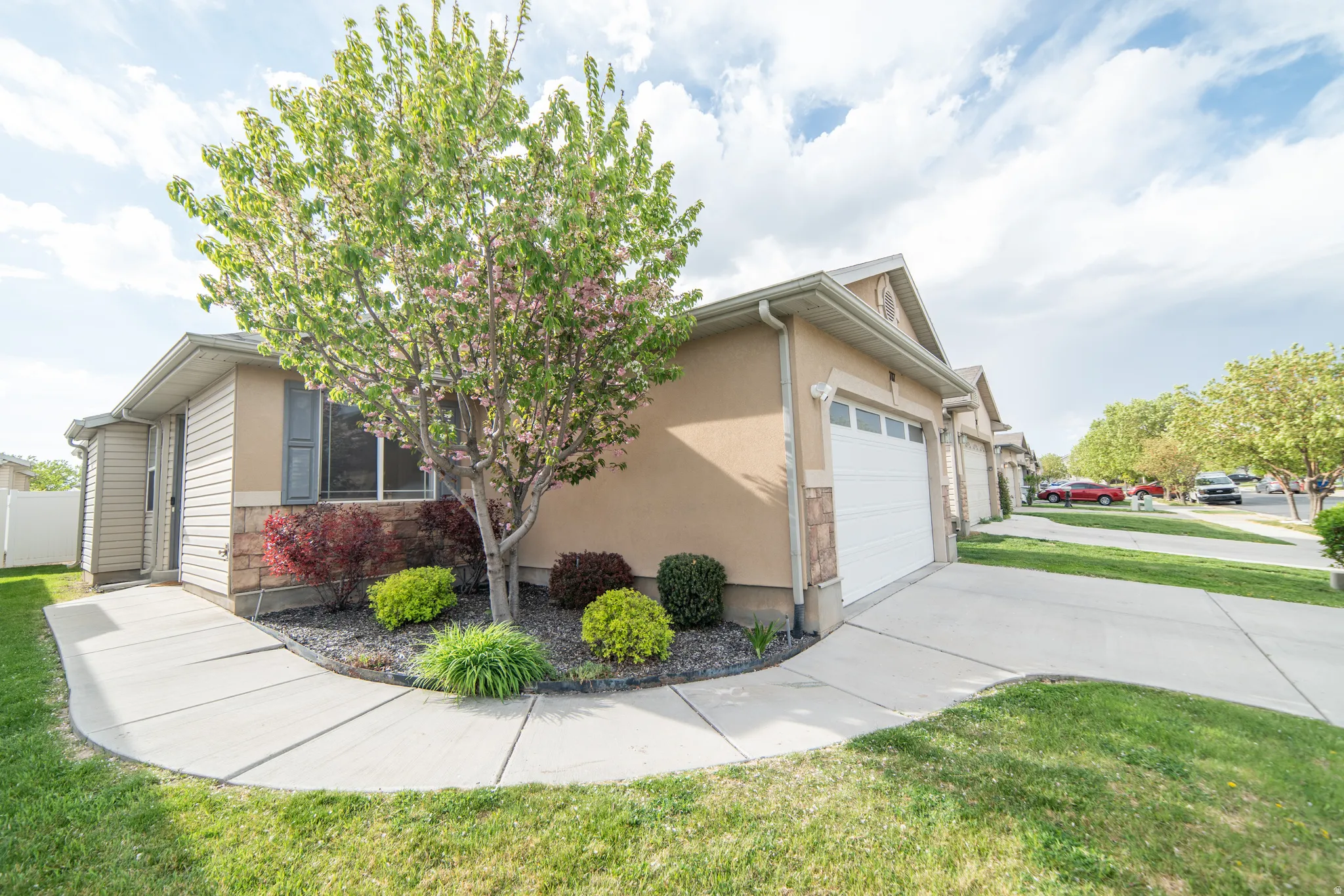 View of property exterior featuring an attached garage, driveway, a yard, stone siding, and stucco siding