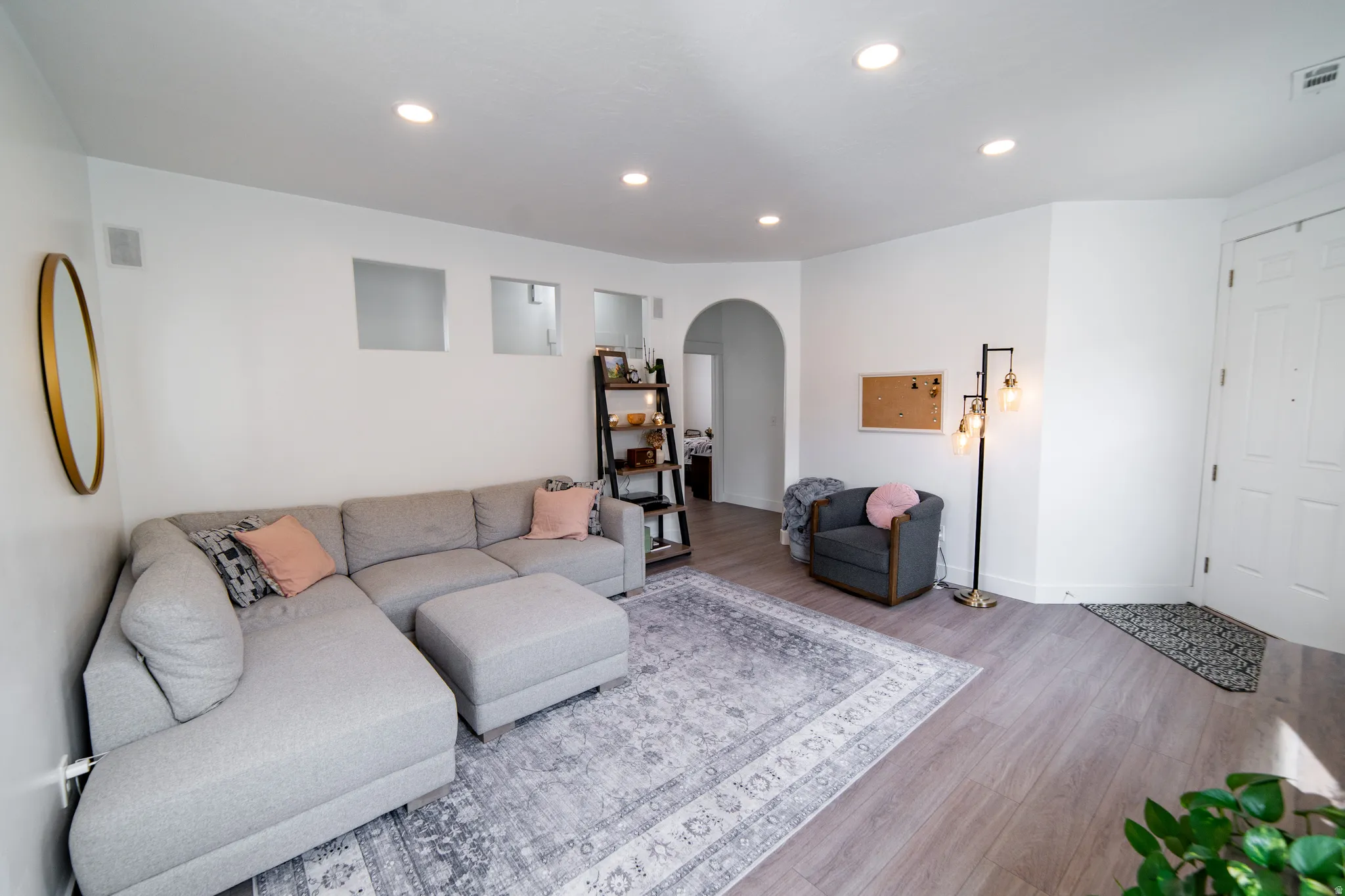 Living room featuring arched walkways, wood finished floors, and recessed lighting