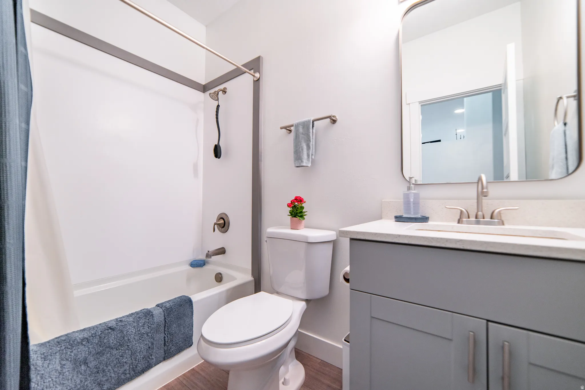 Bathroom with vanity, shower / bath combination with curtain, and dark wood-style floors
