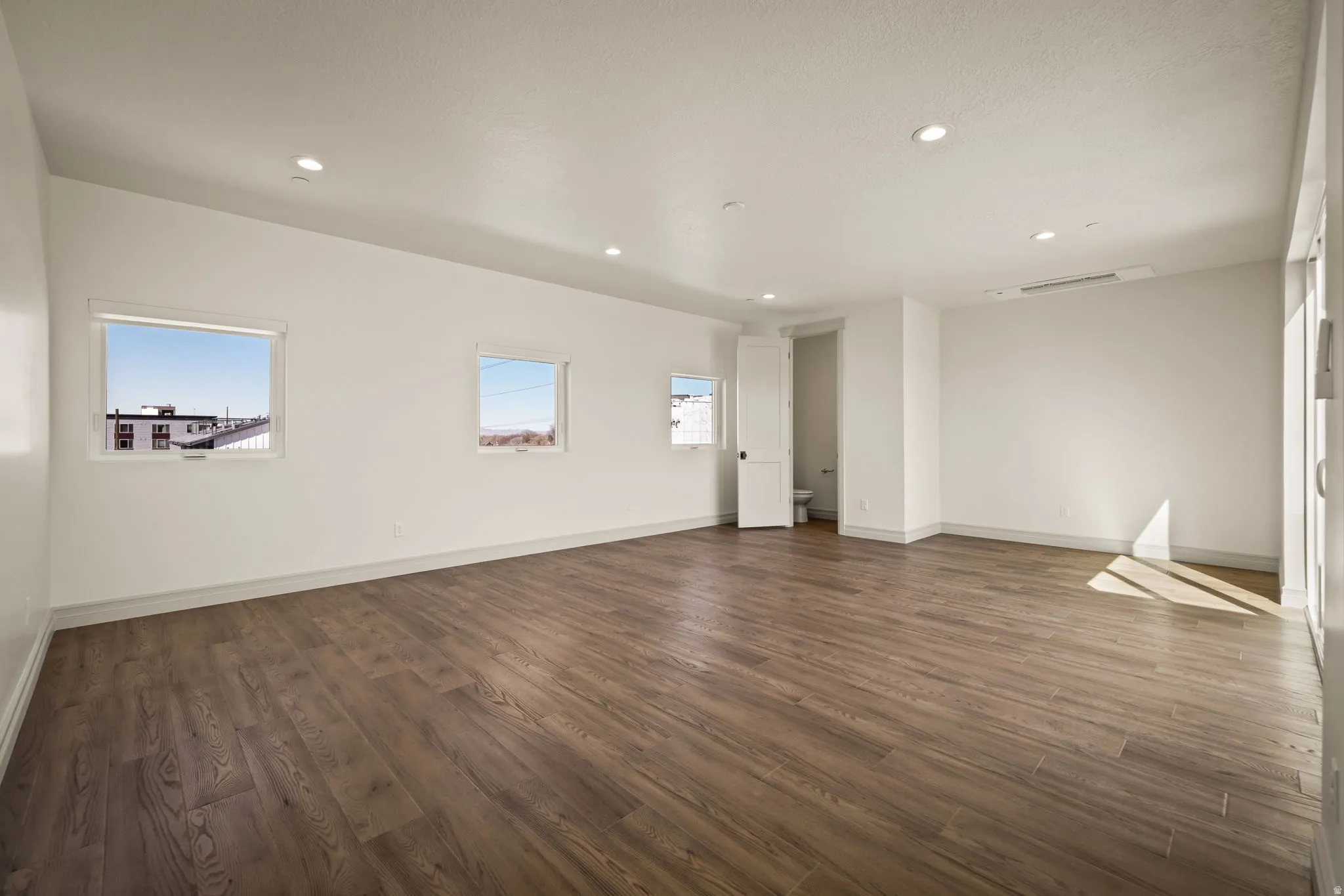 Empty room featuring dark wood-style floors and recessed lighting