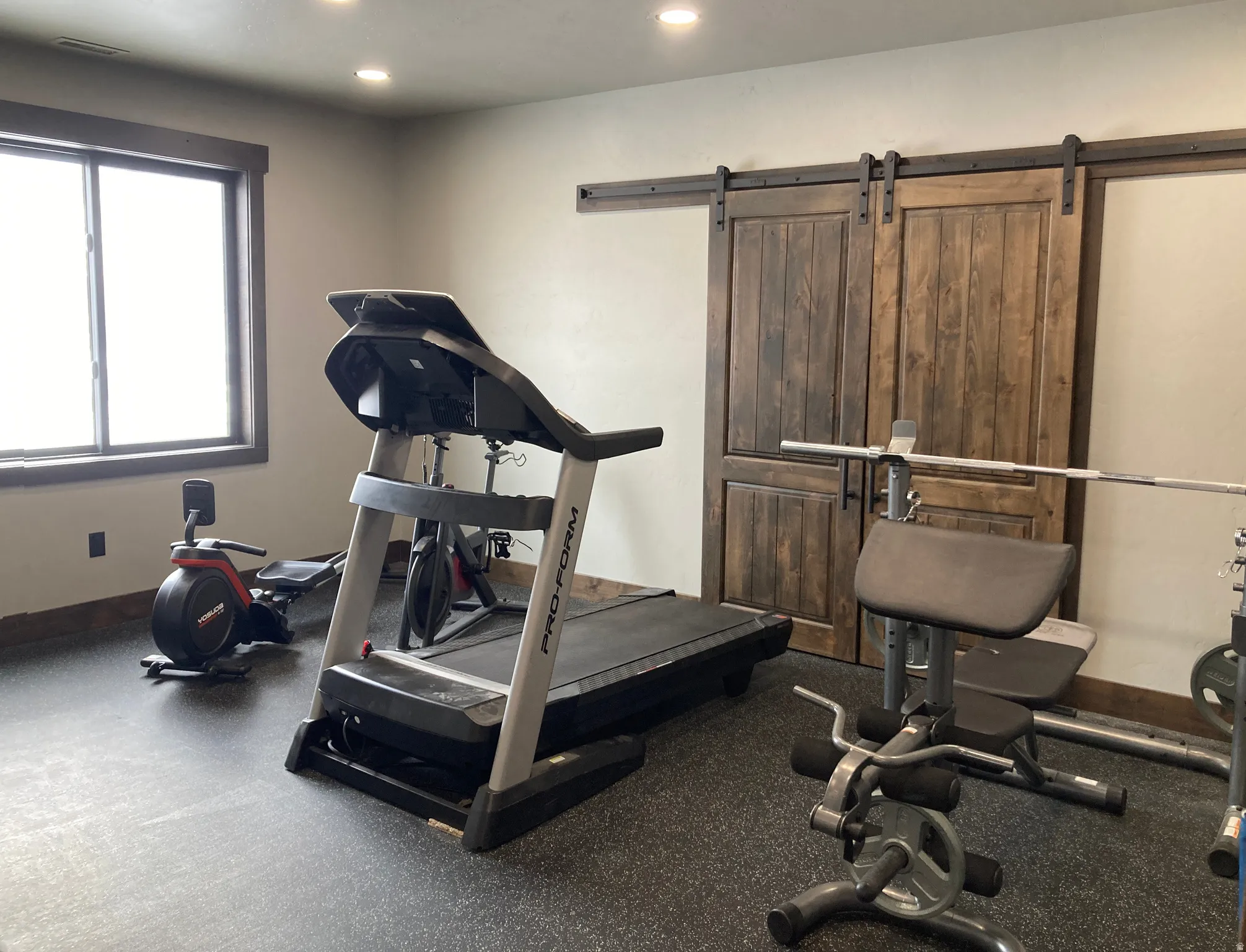 Exercise room with rubber floors, a barn door, and recessed lighting