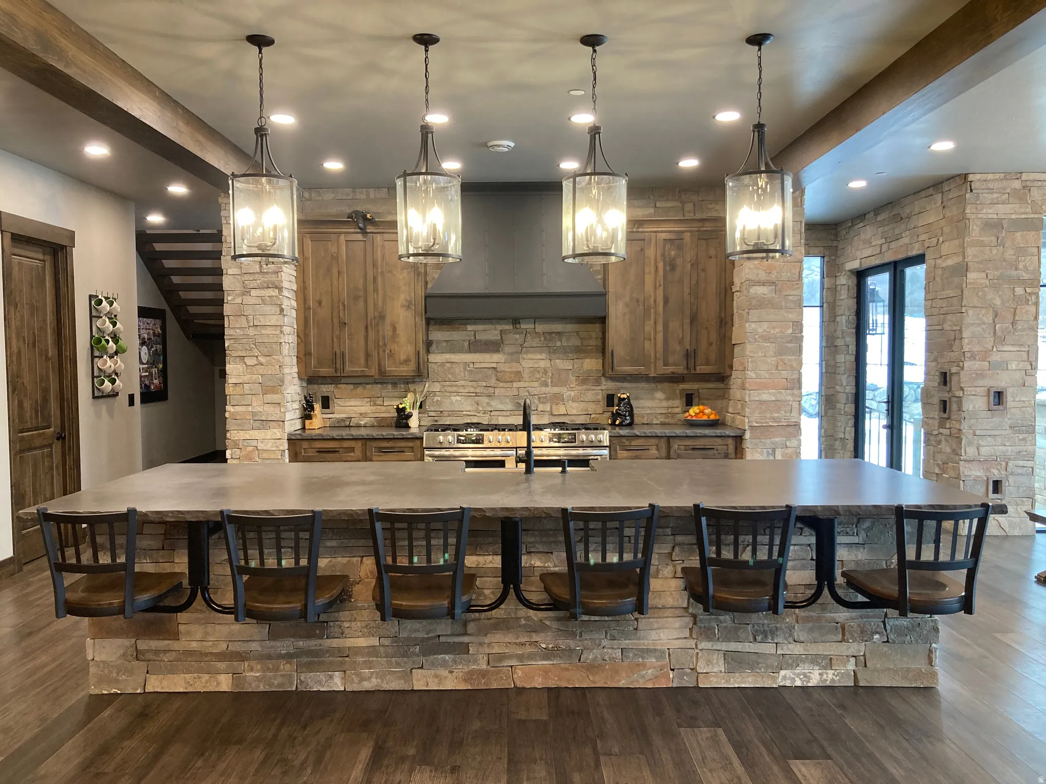 Kitchen with a kitchen bar, a large island with sink, dark wood-type flooring, and wood finish cabinets