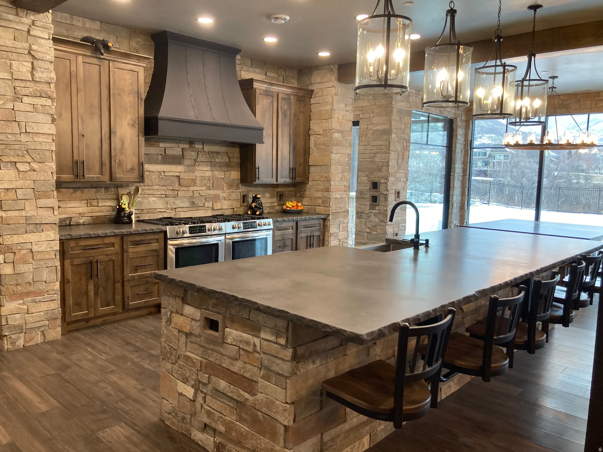 Kitchen with double oven range, a large island, a breakfast bar, and dark wood-style floors