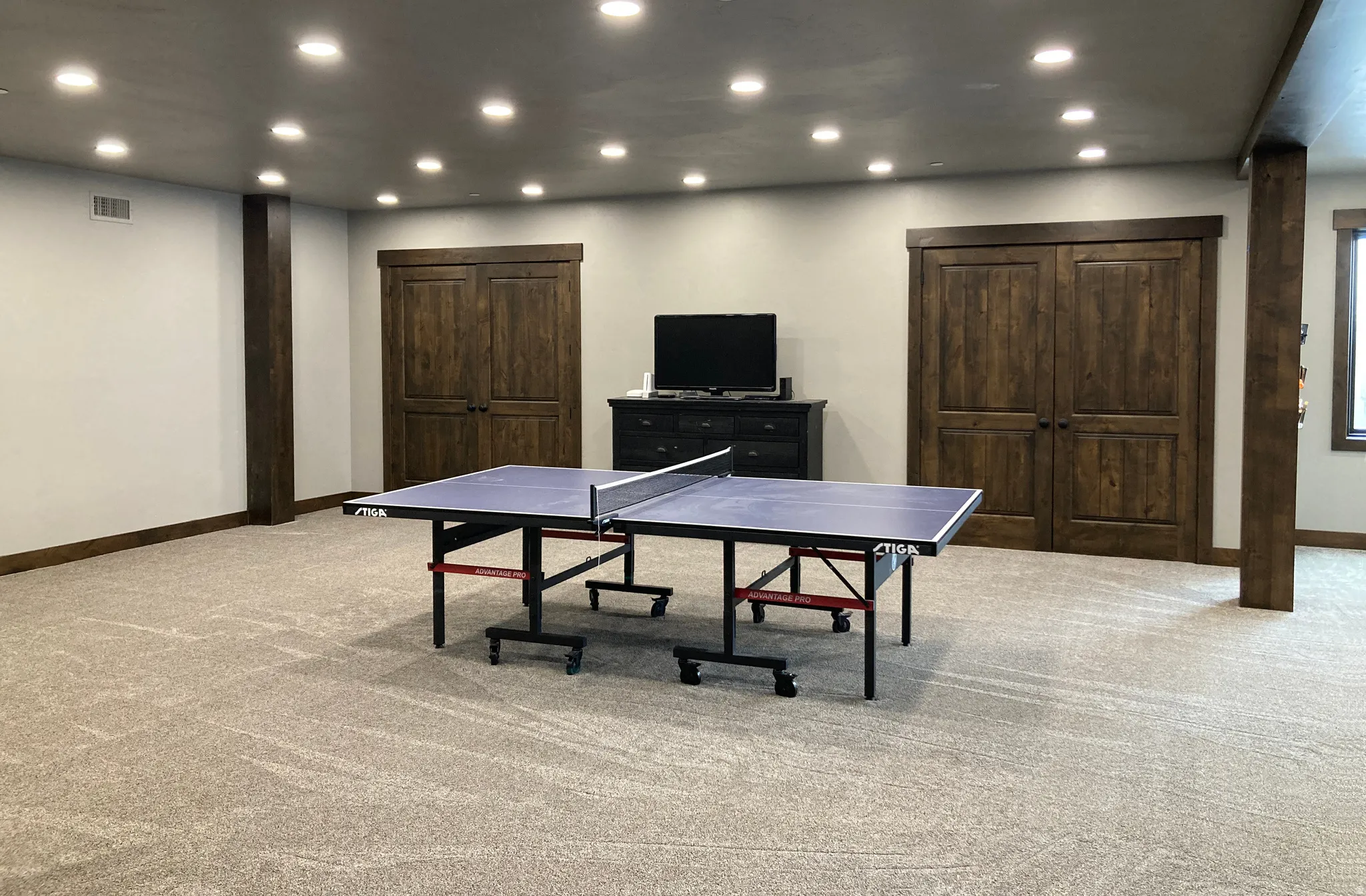 Recreation room with light colored carpet and recessed lighting