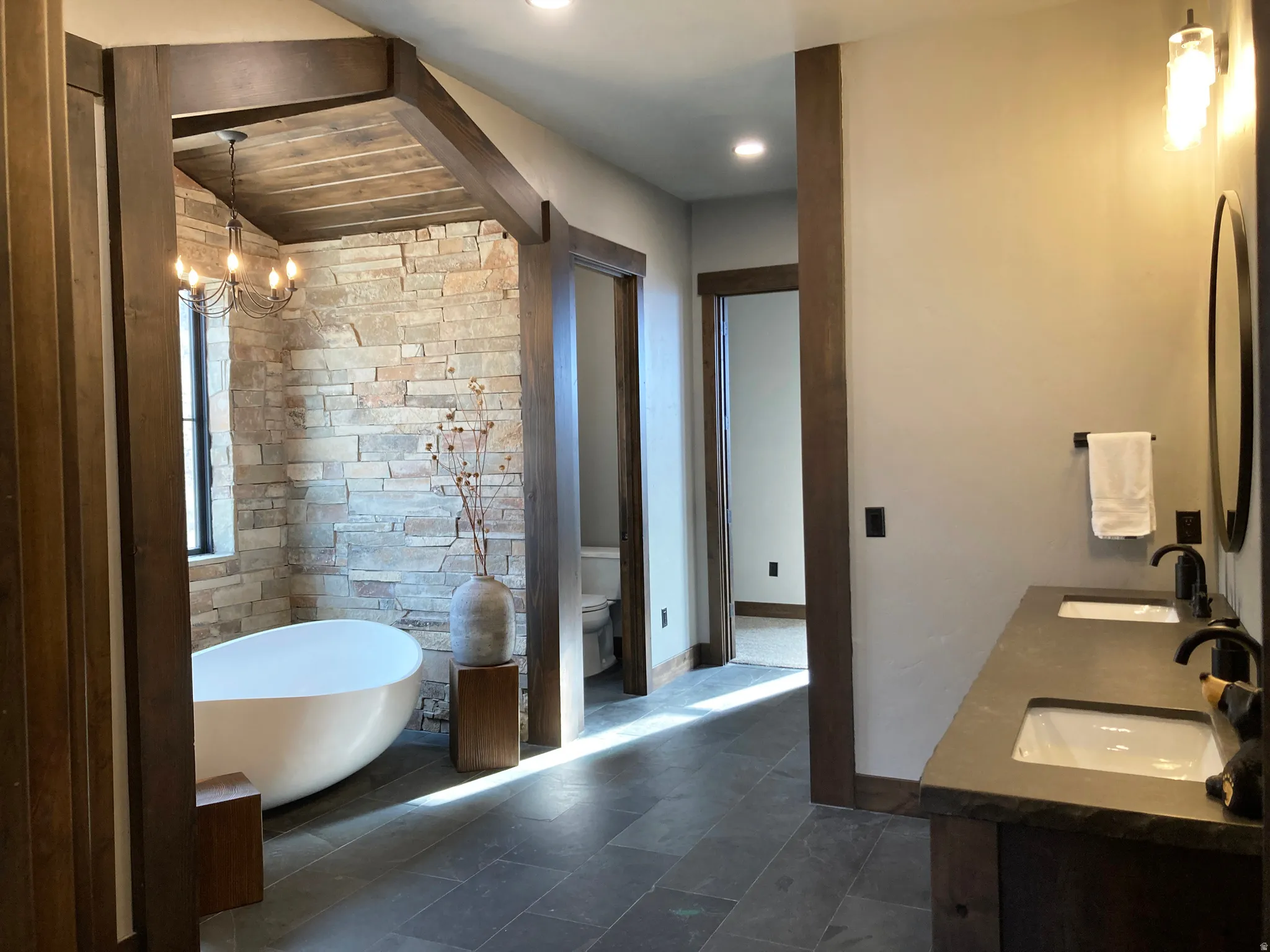 Full bathroom with double vanity, a soaking tub, and hanging lights