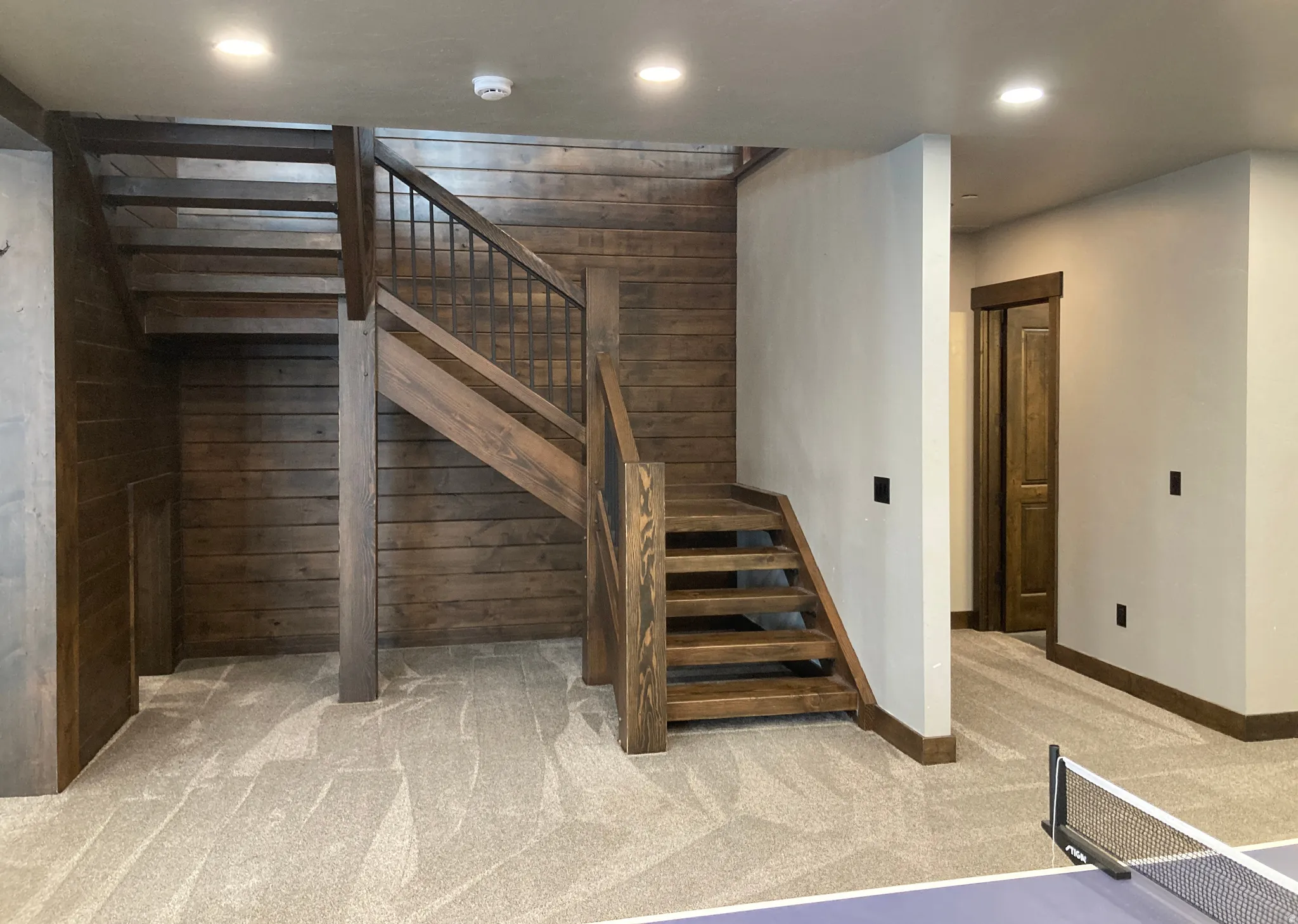 Staircase with carpet, wooden walls, and recessed lighting
