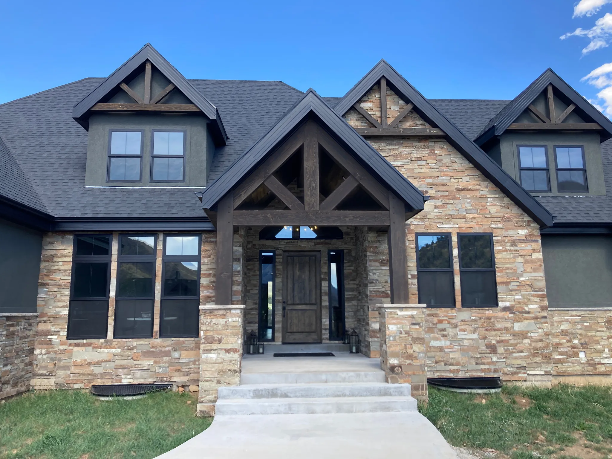 Property entrance with stone siding, a porch, and roof with shingles