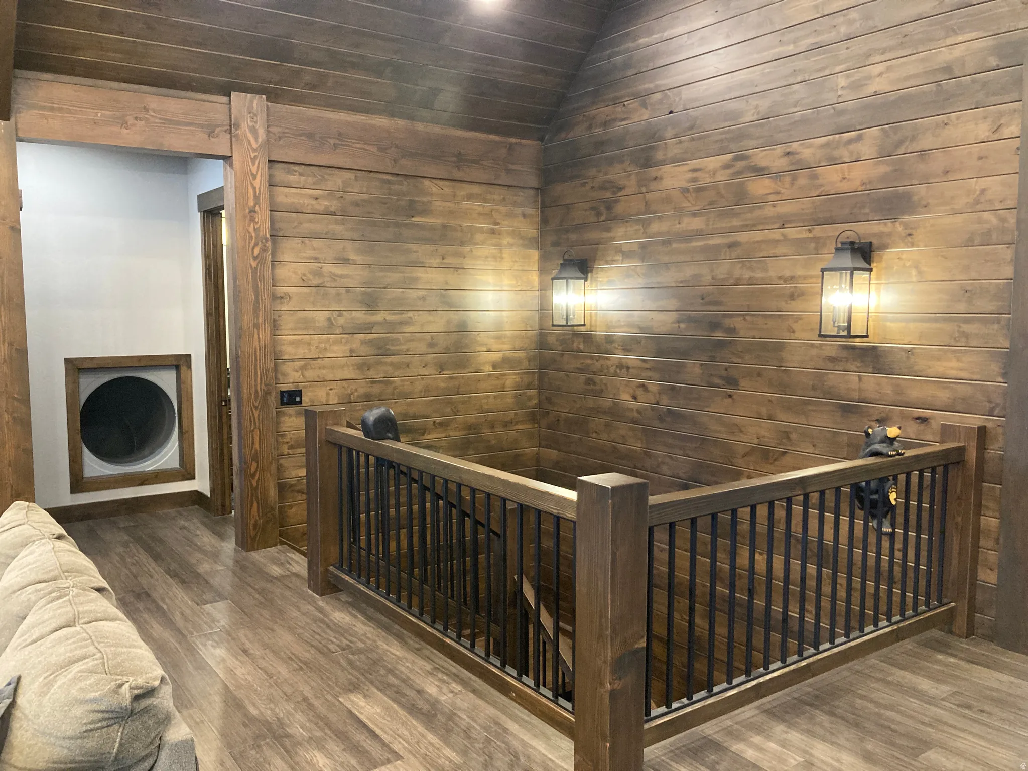 Hall featuring an upstairs landing, wooden walls, wood finished floors, and lofted ceiling