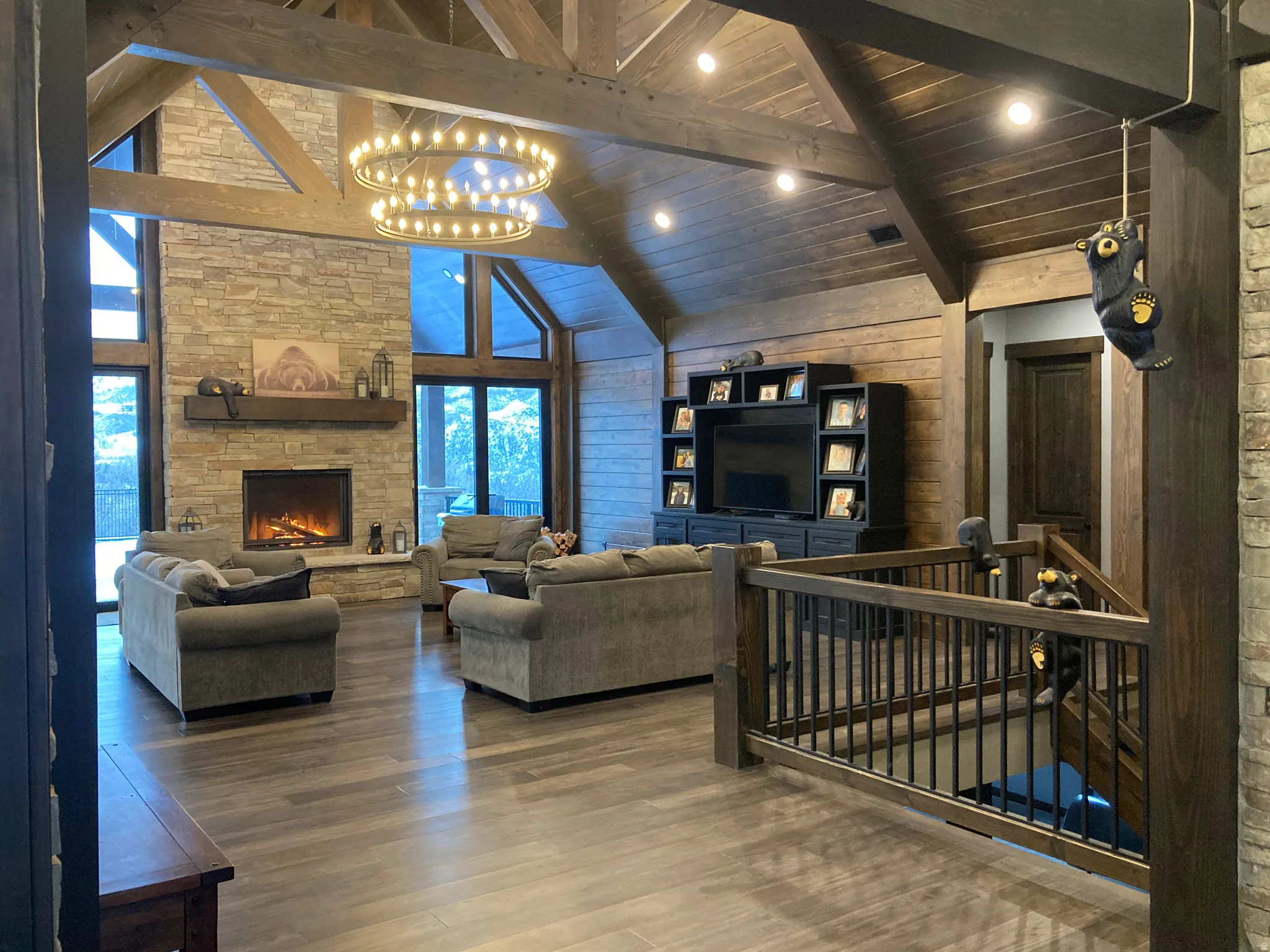 Living room with a high wooden beamed ceiling, wood finished floors, hanging lights, a fireplace, and wood walls