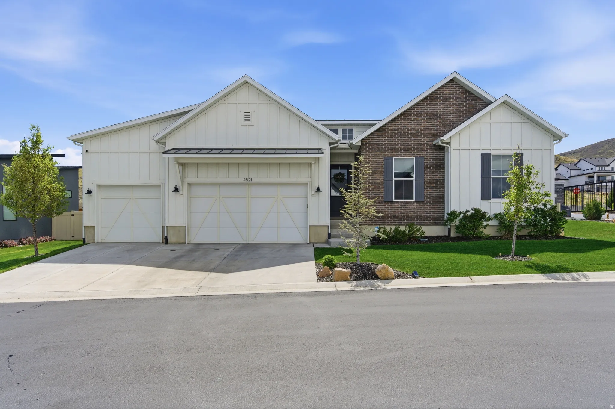 Modern craftsman-style residence featuring a combination of white board-and-batten siding and dark brick accents