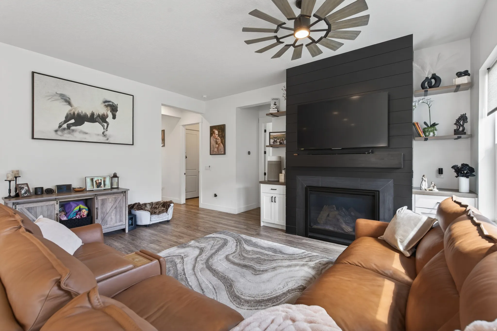 Living area with a large fireplace, wood finished floors, and ceiling fan