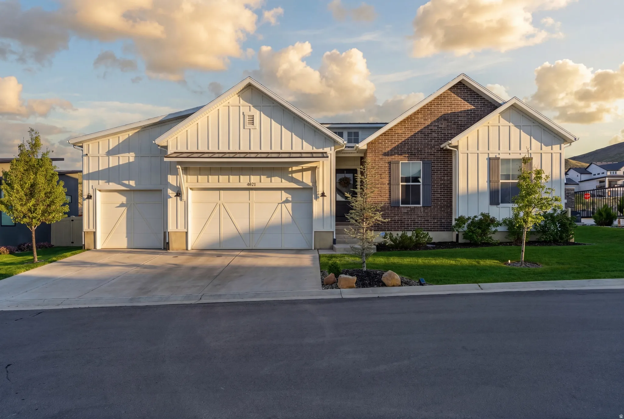 Modern farmhouse style home featuring board and batten siding, concrete driveway, an attached garage, a front lawn, and brick siding