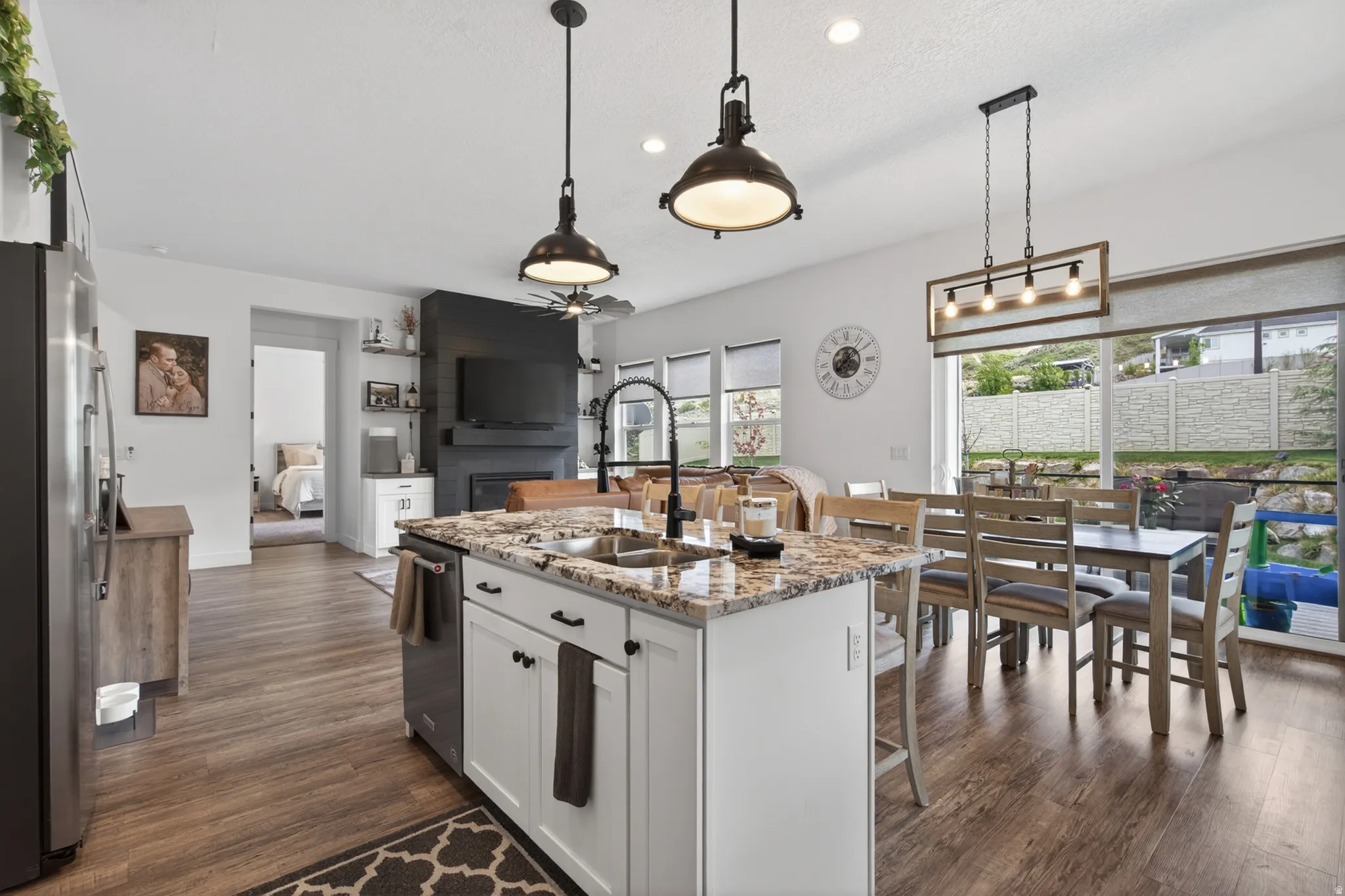 Kitchen with white cabinets, light stone countertops, dark wood-style floors, open floor plan, and stainless steel appliances