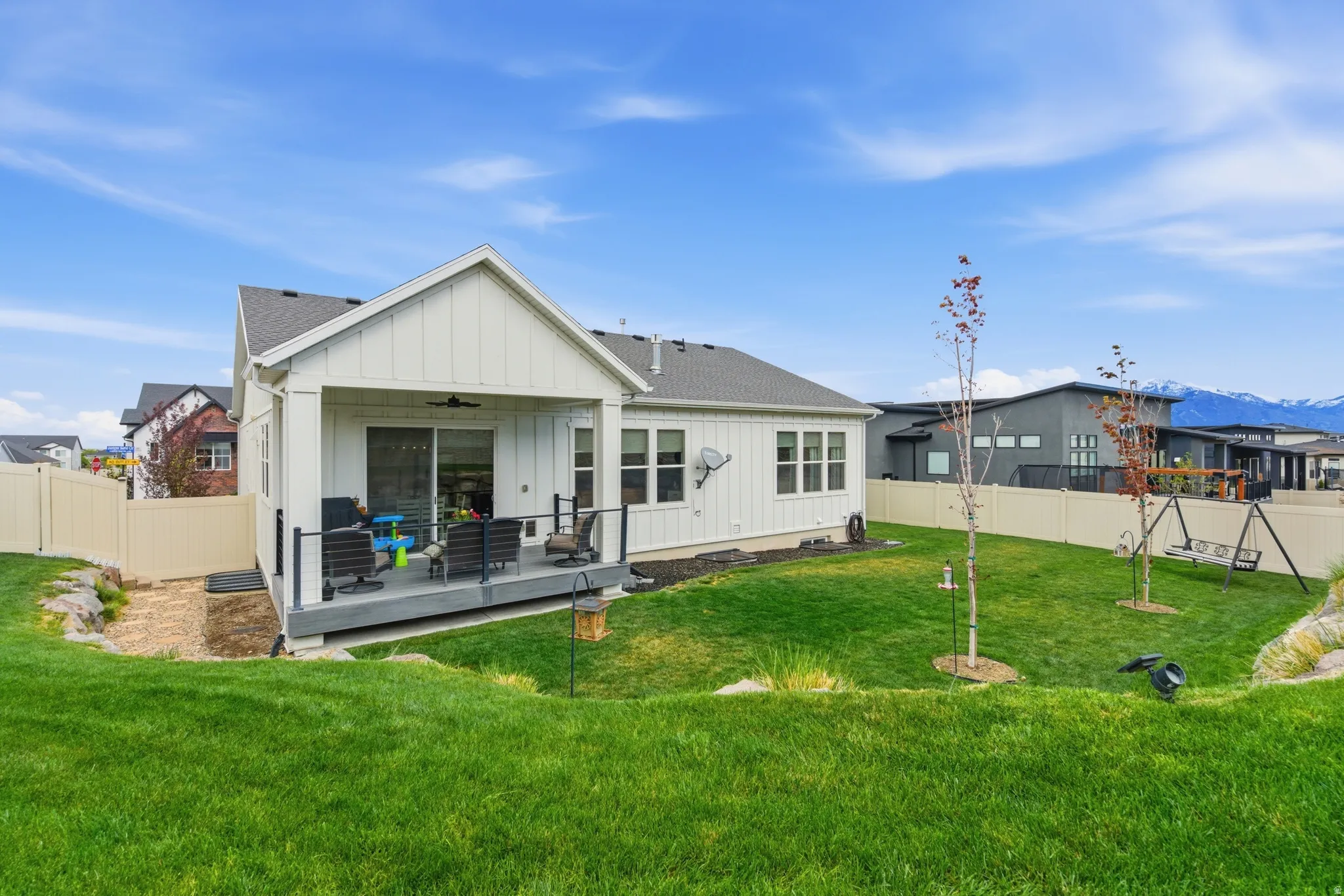 Rear view of house featuring board and batten siding, a fenced backyard, a wooden deck, and ceiling fan