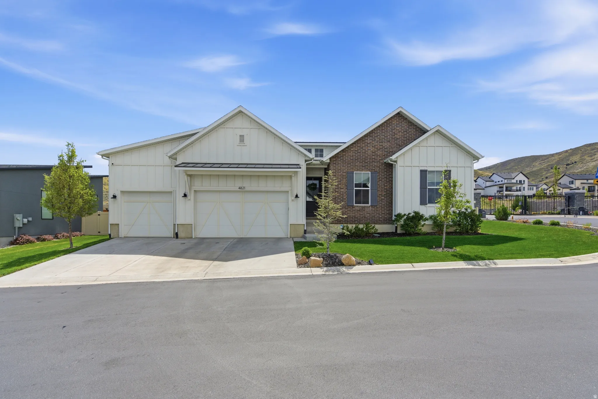 View of front of property featuring board and batten siding, a front yard, a garage, driveway, and a standing seam roof