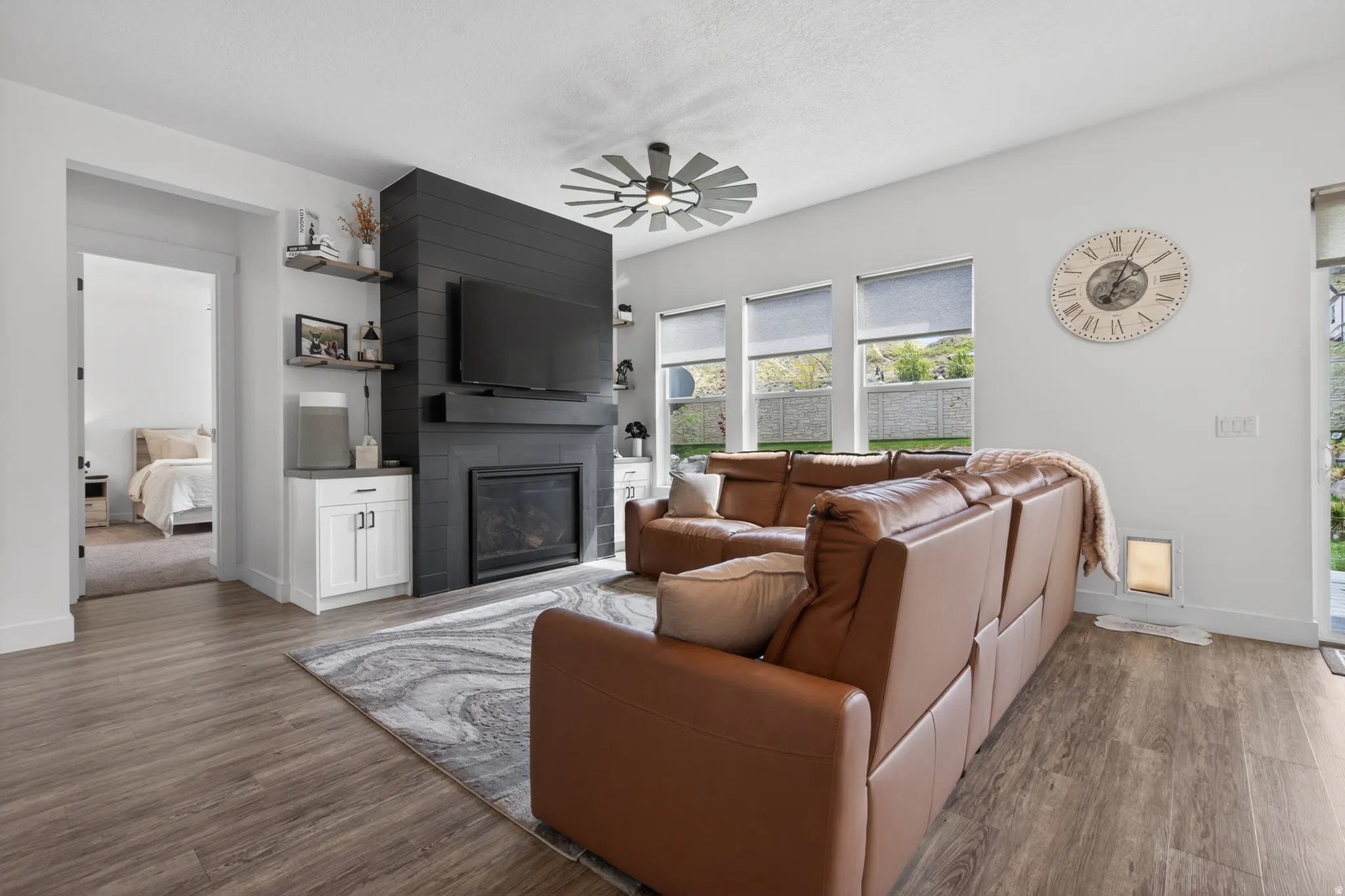 Living room featuring dark wood-type flooring, a fireplace, and a ceiling fan
