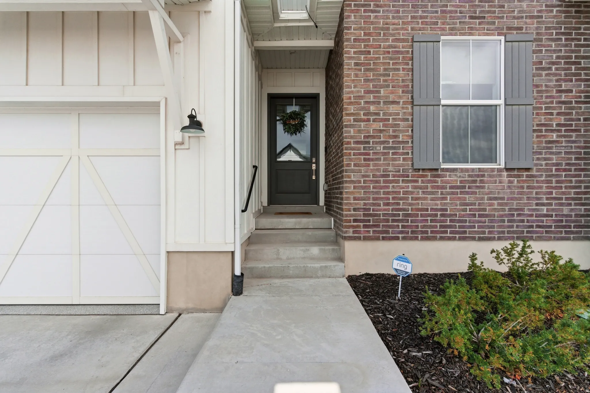View of exterior entry featuring brick siding, board and batten siding, and an attached garage