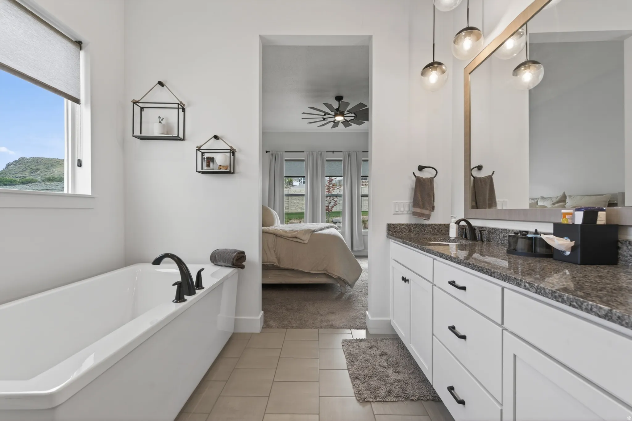 Ensuite bathroom with vanity, a soaking tub, ceiling fan, and light tile patterned flooring