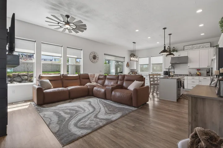 Open-concept living space featuring wood-finish flooring, recessed lighting, and a unique ceiling fan