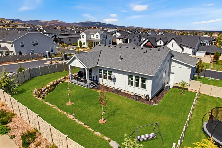 Expansive backyard with manicured lawn, established landscaping, and a covered patio