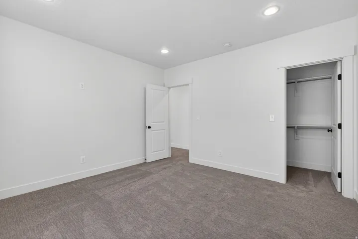 Carpeted room featuring recessed lighting, a standard closet with shelving and hanging rods, and white trim